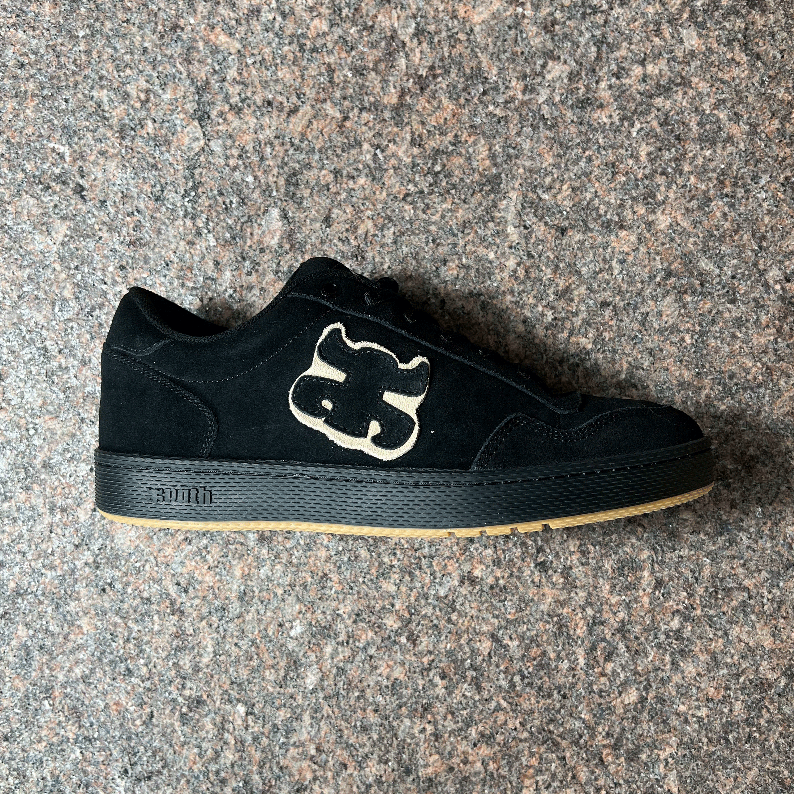 SIDE VIEW OF THE IPATH 1985 MODEL SHOE IN BLACK SUEDE AND BLACK SOLE WITH BOTTOM GUM TRIM