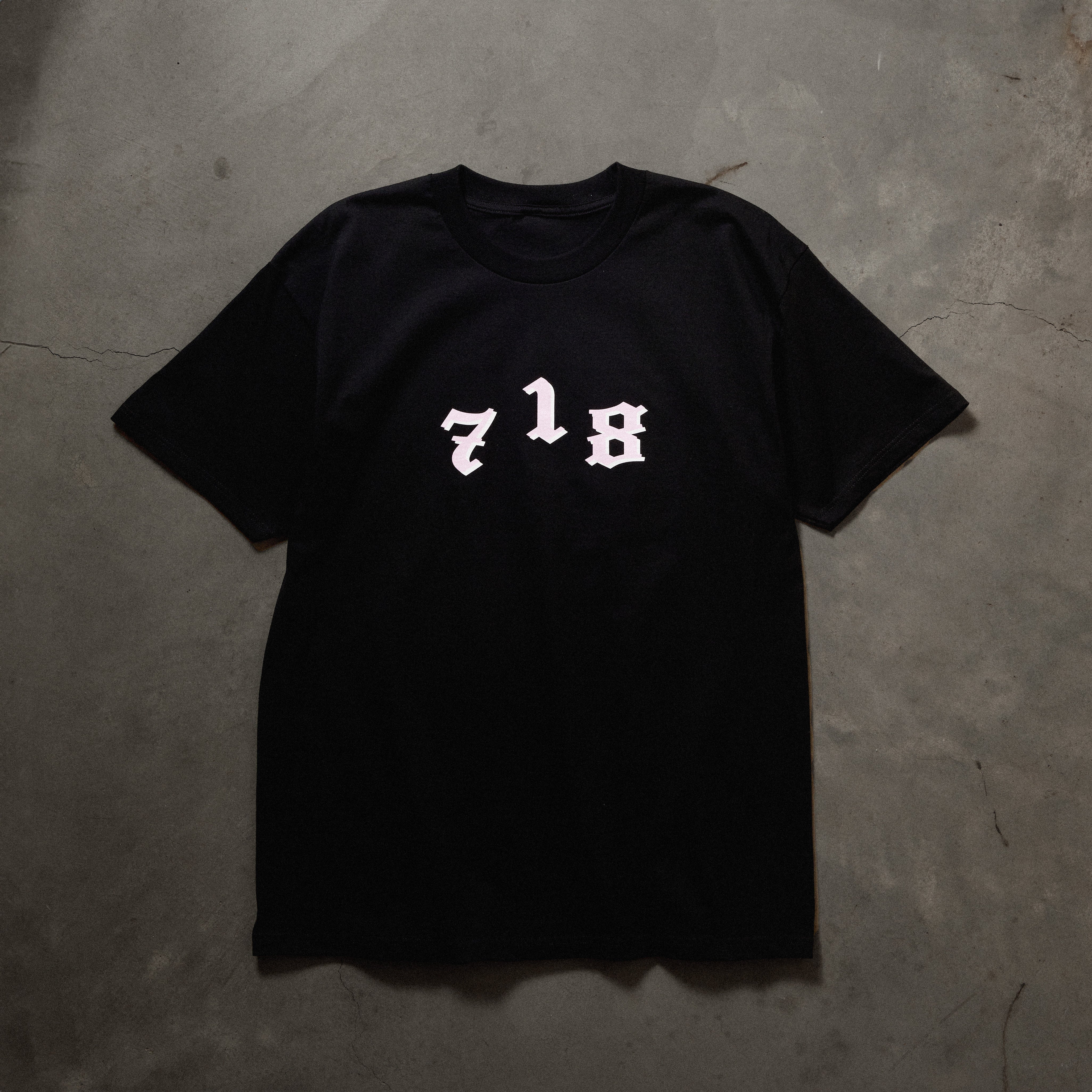 Full front image of black tee with 718 area code printed in white.