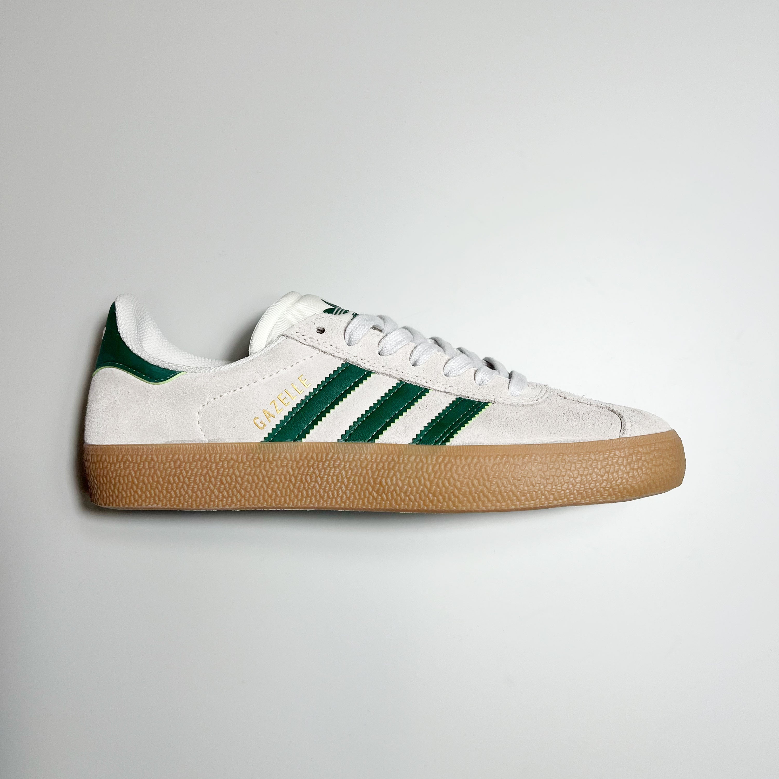 SIDE VIEW ADIDAS GAZELLE ADV IN CRYSTAL WHITE SUEDE, GREEN LEATHER STRIPES AND HEEL TAB WITH GUM SOLE.