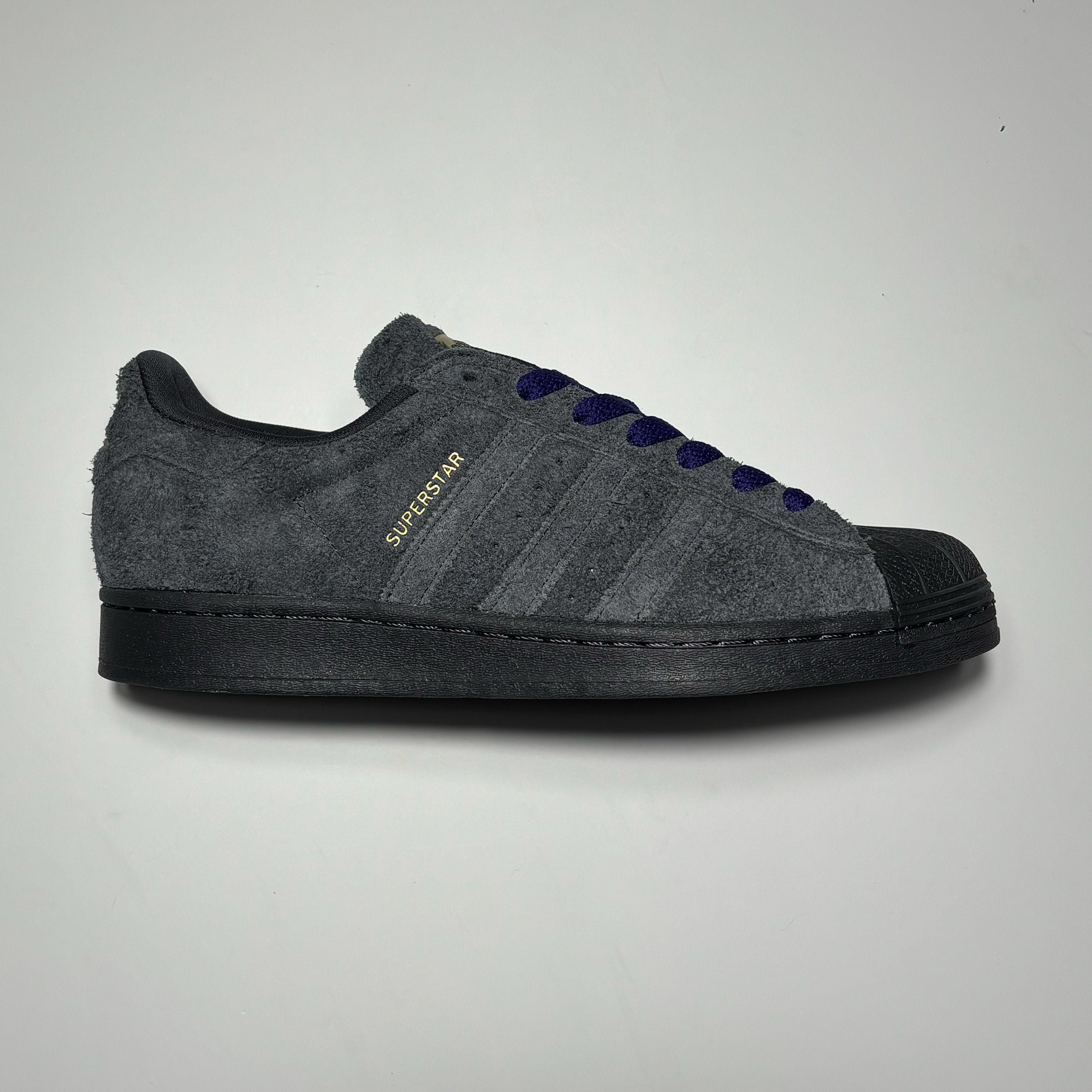 Side image of right shoe. Carbon suede with purple laces.