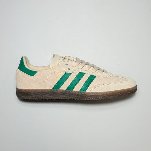 A classic Adidas Samba ADV sneaker in cream suede with green stripes and a green heel tab, featuring a brown gum sole, shown from a side profile on a light gray background.
