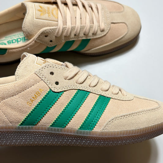 Close detail of Adidas Samba ADV in cream suede with green stripes. Samba text in gold on heel panel.