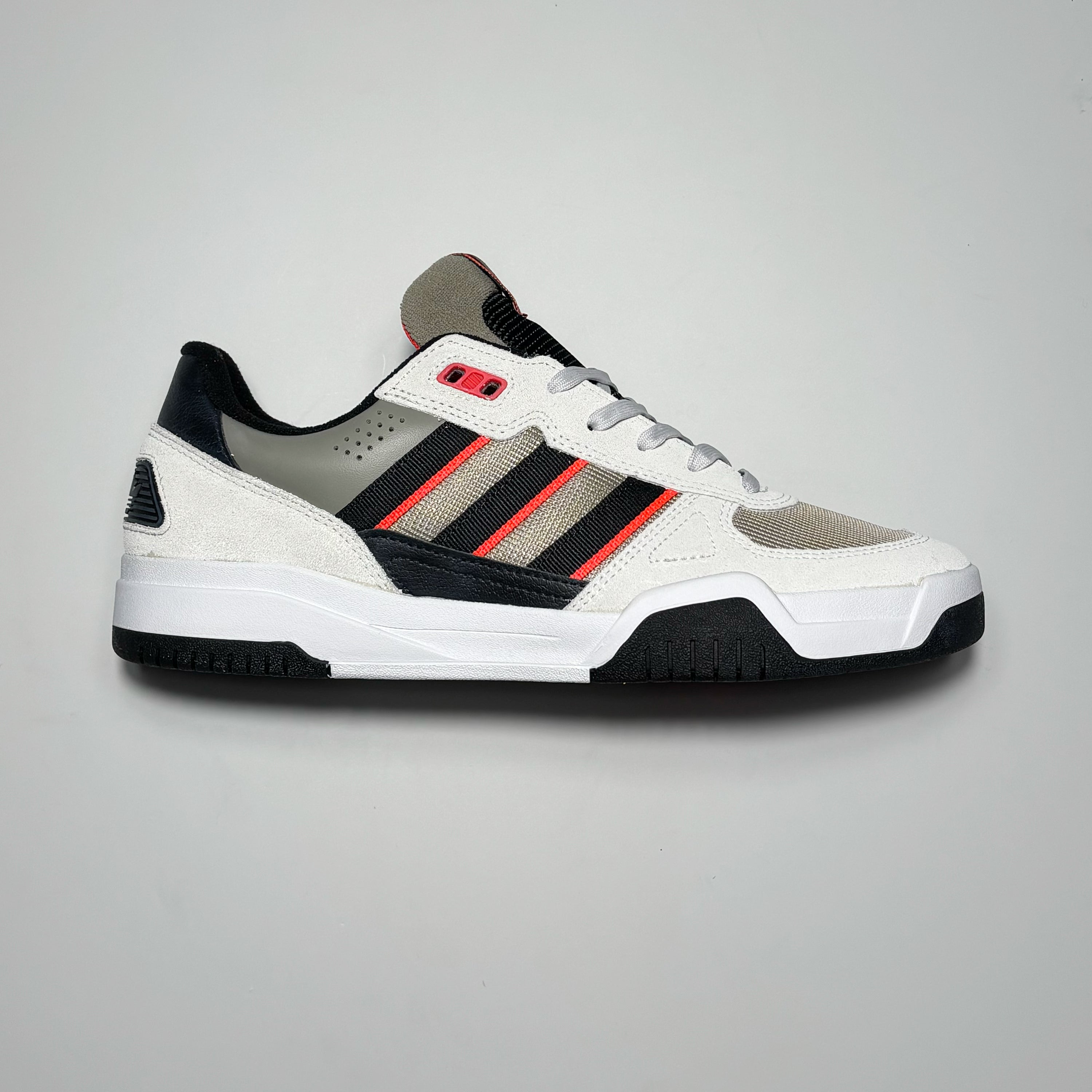 Side image of right shoe. White/grey suede with black/orange stripes and mesh toe box.