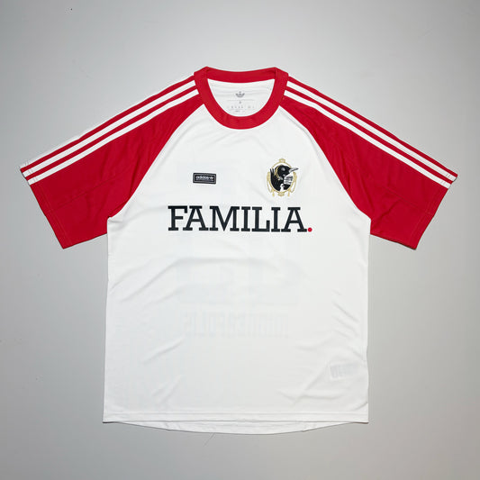 A white and red short-sleeve raglan soccer jersey with 'FAMILIA' printed across the chest, featuring three white stripes on the sleeves and a black-and-white loon crest on the left chest.