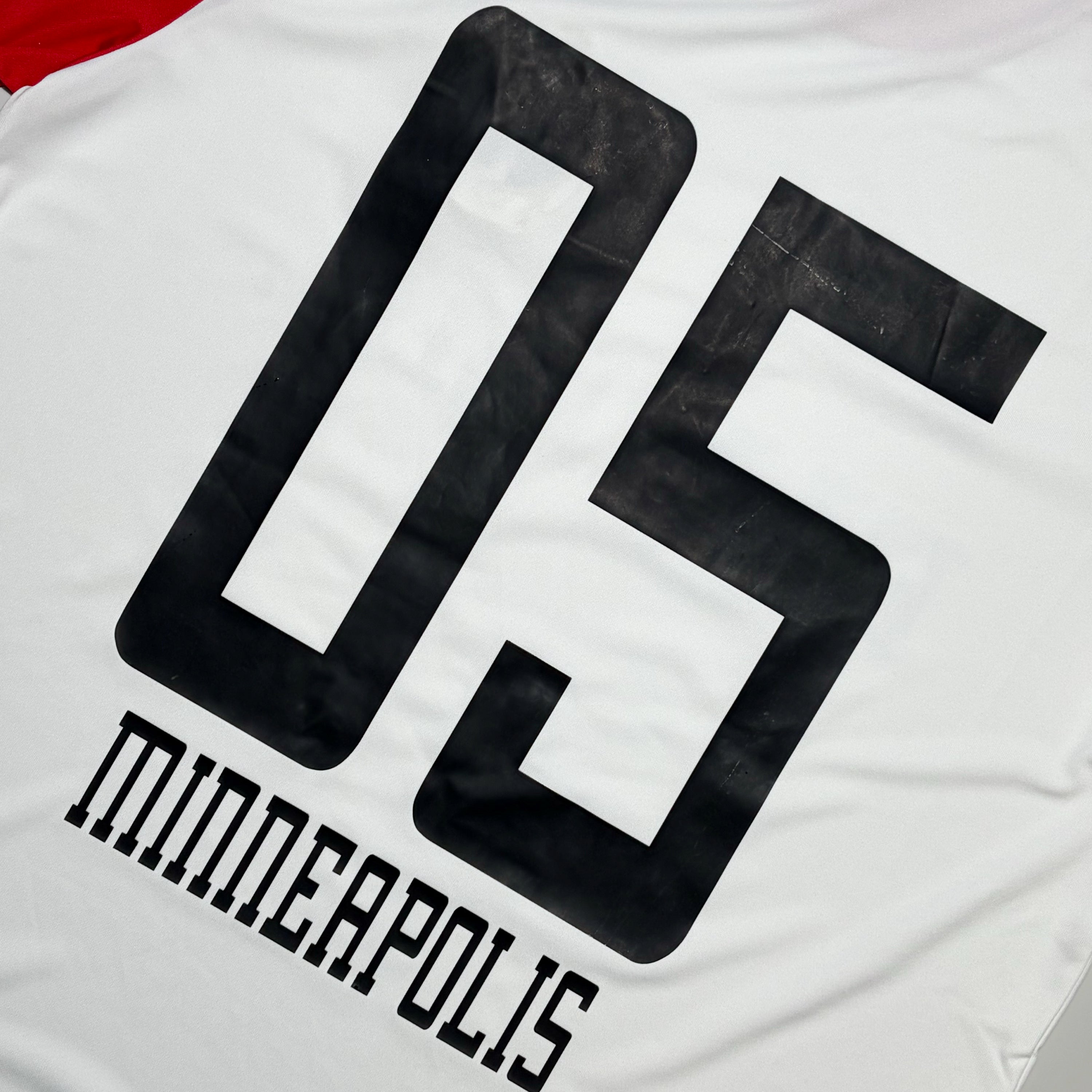 Close-up of the back of a white sports jersey with a large black number 05 and the word MINNEAPOLIS printed below in black block letters.