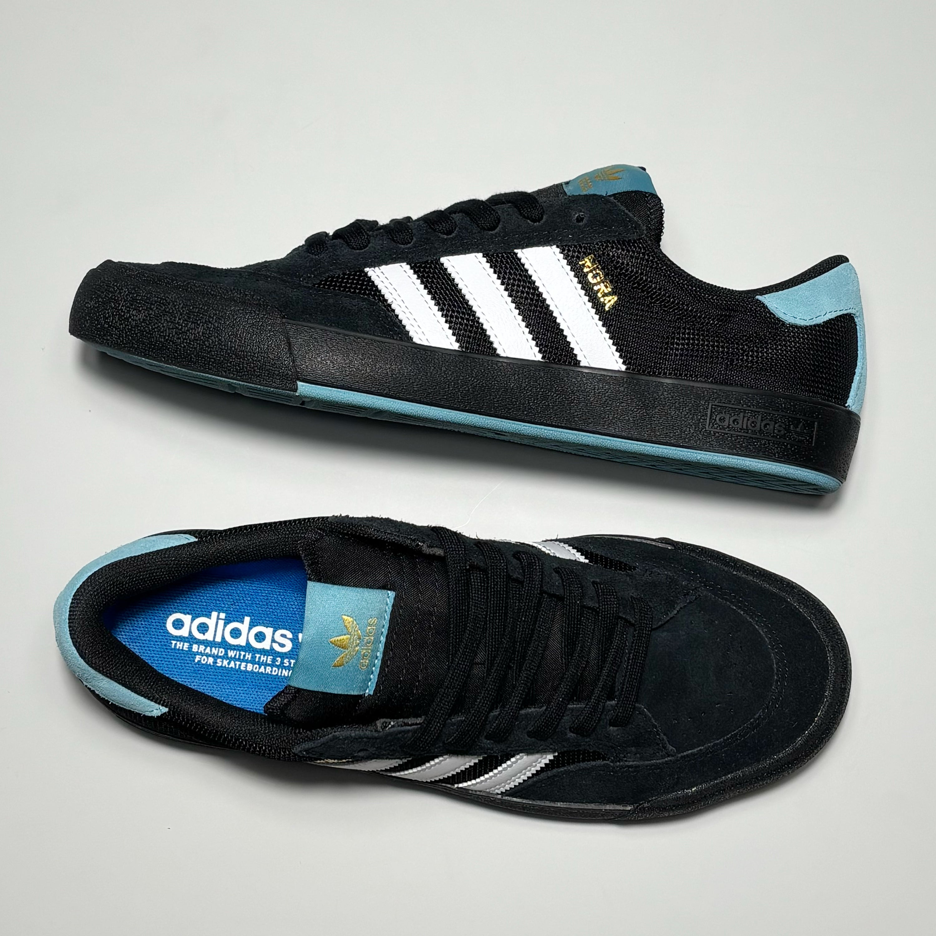 Toe down view with side profile.
Nora in gold printed on heel panel and adidas branding on tongue.