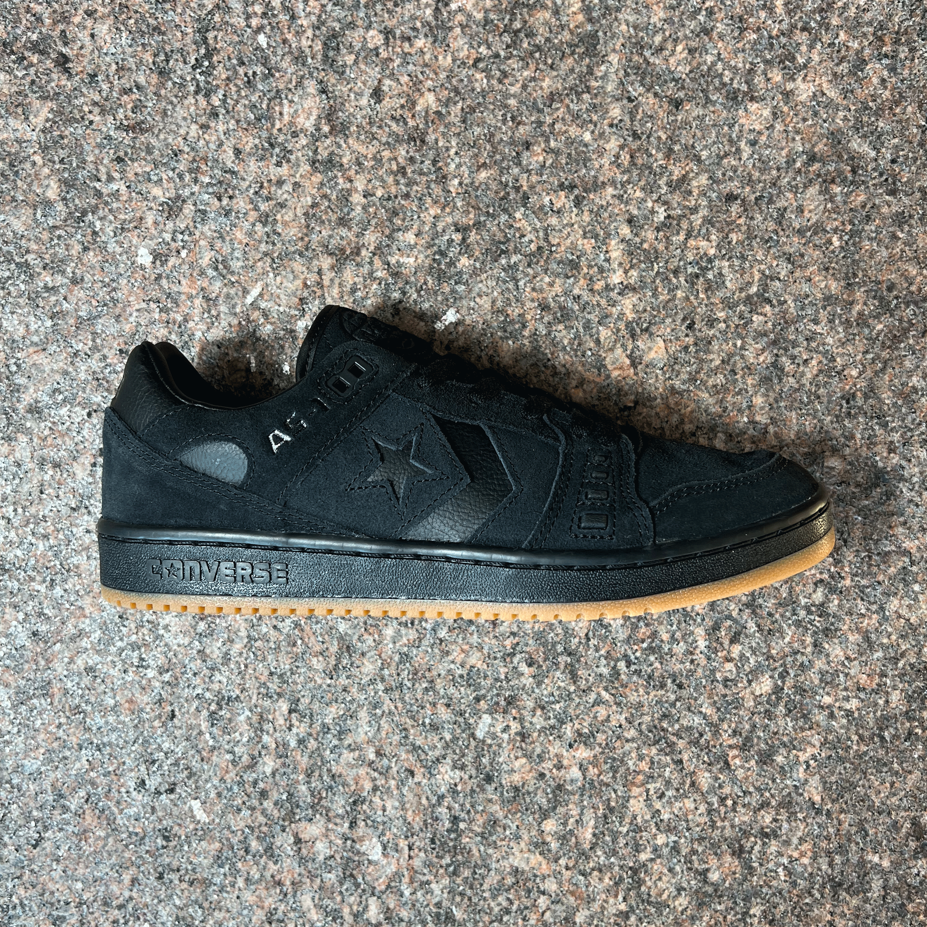 SINGLE CONVERSE CONS AS-1 SHOE IN BLACK SUEDE WITH A BLACK AND GUM SOLE DISPLAYED ON GRANITE