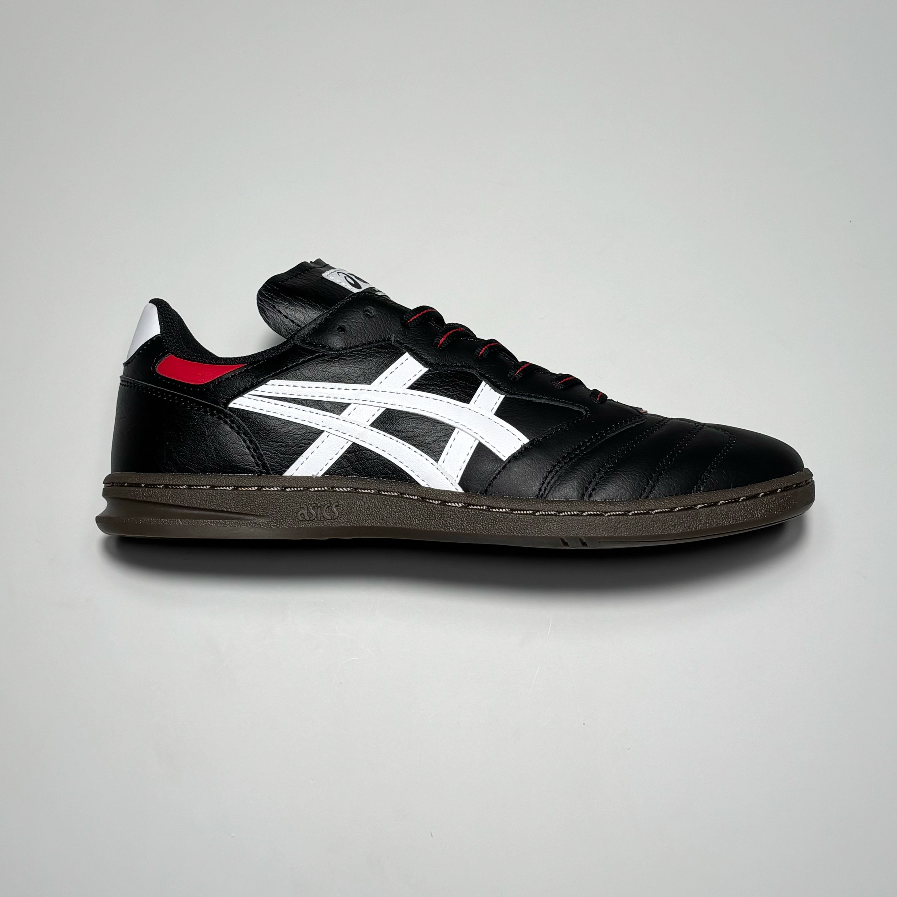Side image of right shoe. Premium black leather with white asics branding and gum outsole.