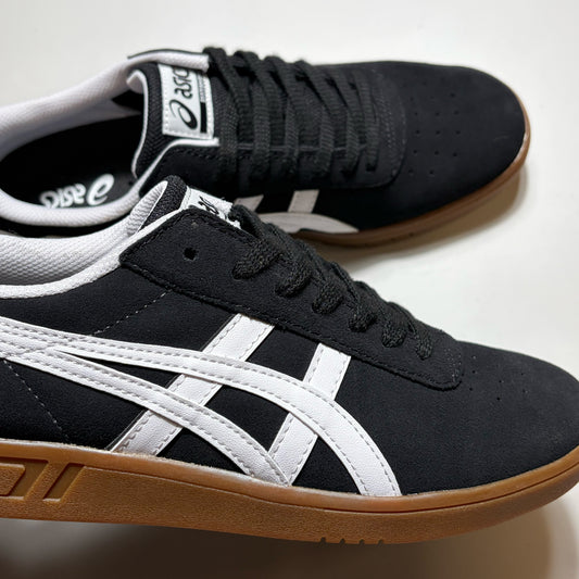 Black and white Asics skate shoes with a brown gum sole, shown on a light off-white background.