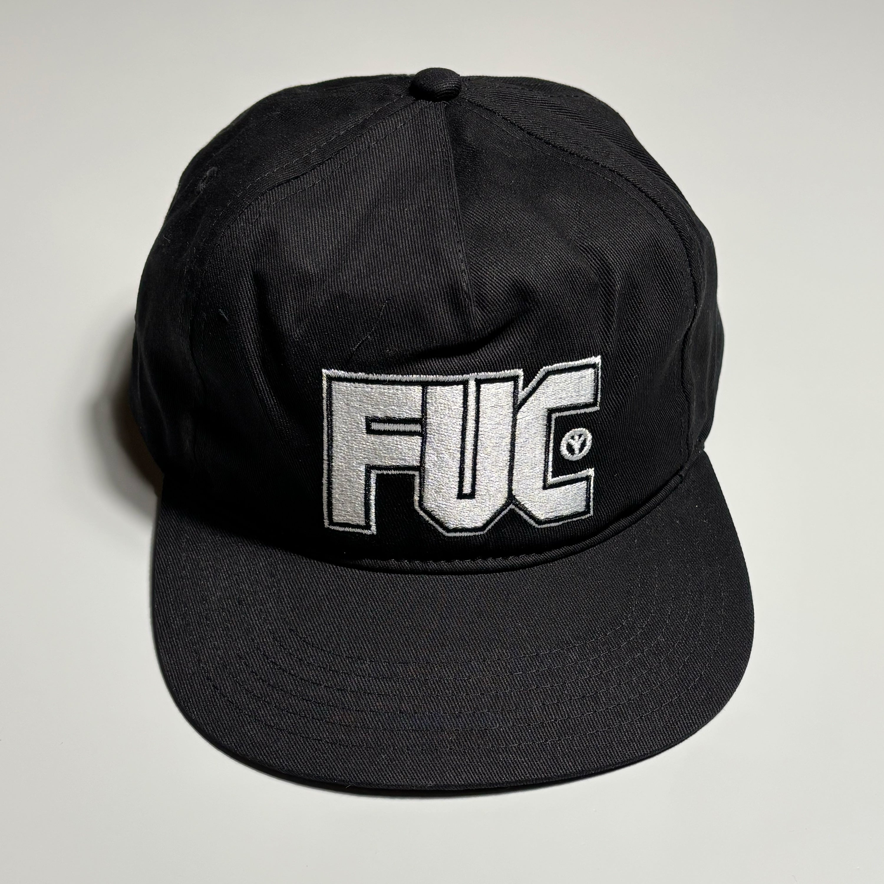 Front image of black hat with white embroidery on crown.