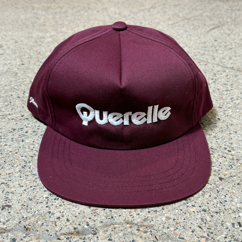 Front image of burgundy hat. Querelle embroidered font on crown