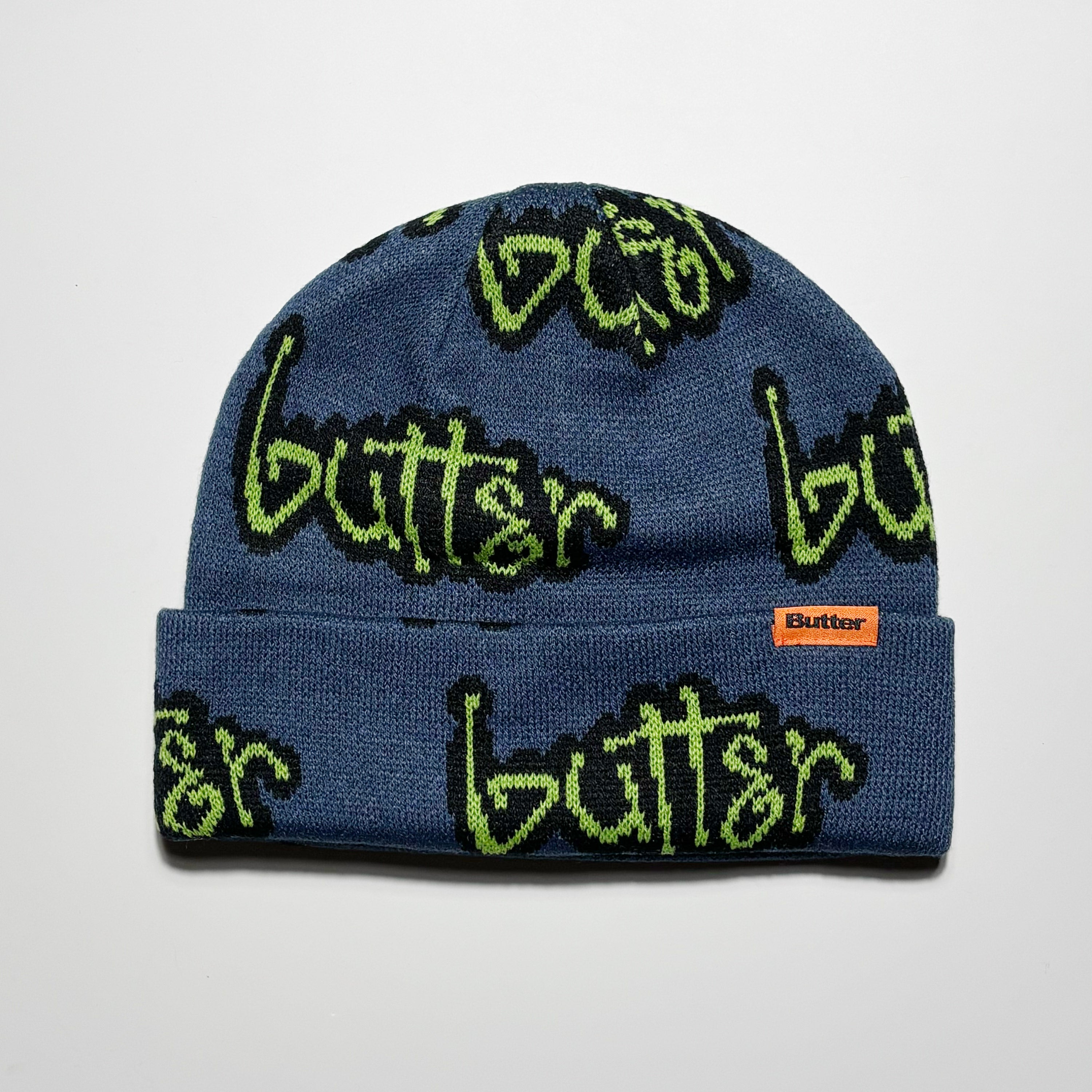 Blue beanie with green text and woven label on fold