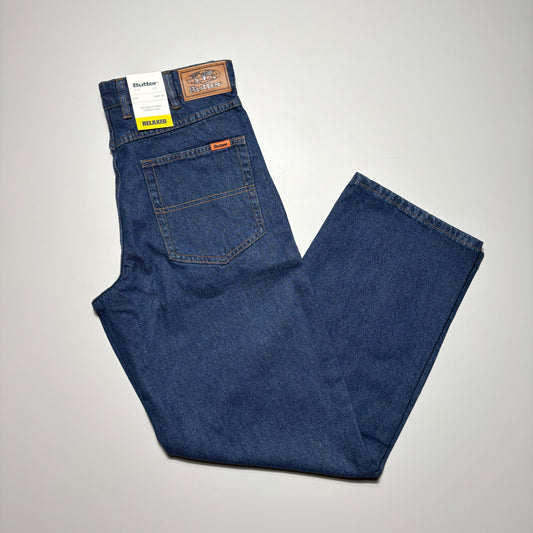 Image of folded dark indigo denim with woven label on back pocket.