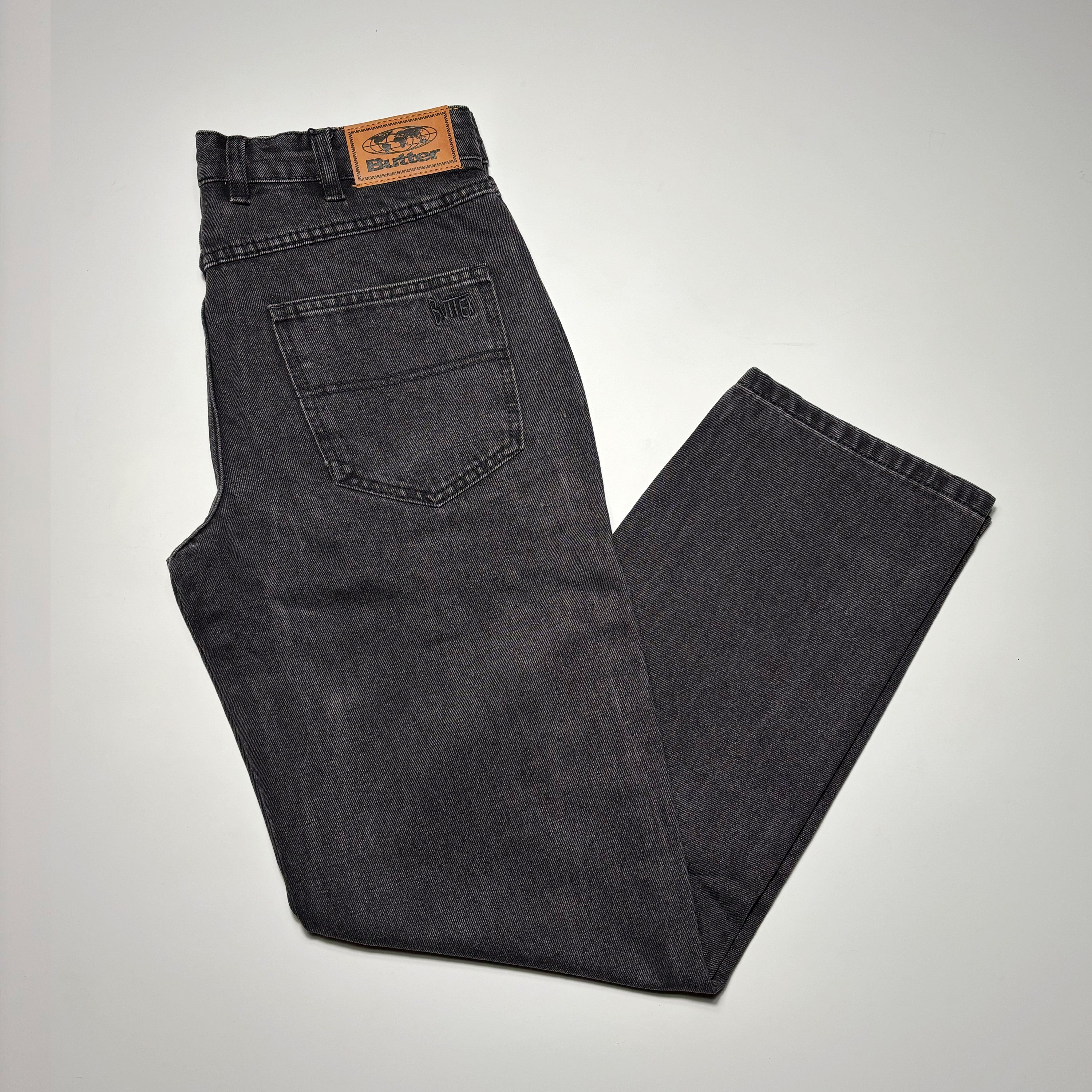 Image of folded denim. Black washed with embroidered logo on back pocket.