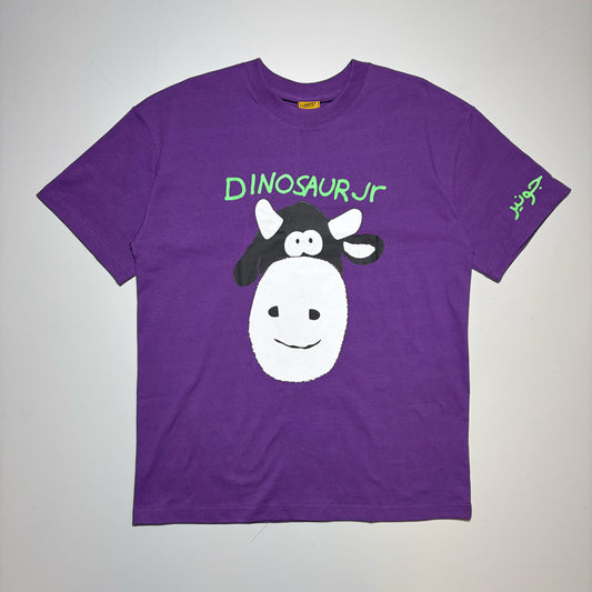 A purple short-sleeve t-shirt featuring a cartoon graphic of a cow with a dinosaur head and the text 'DINOSAURJR' in green on the chest, displayed flat against a light gray background.