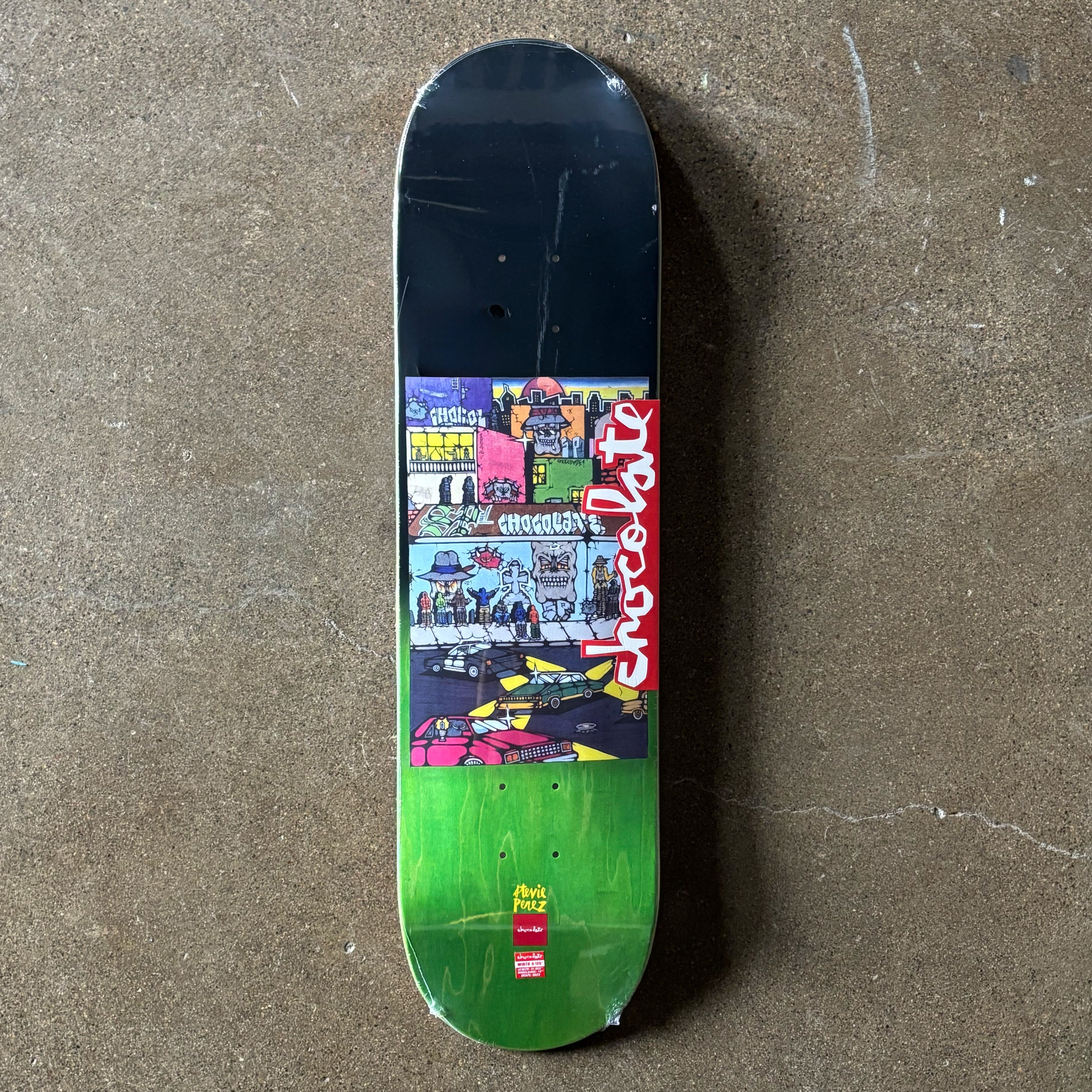 Full image of deck. Cartoon artwork in center. Green veneer on tail.