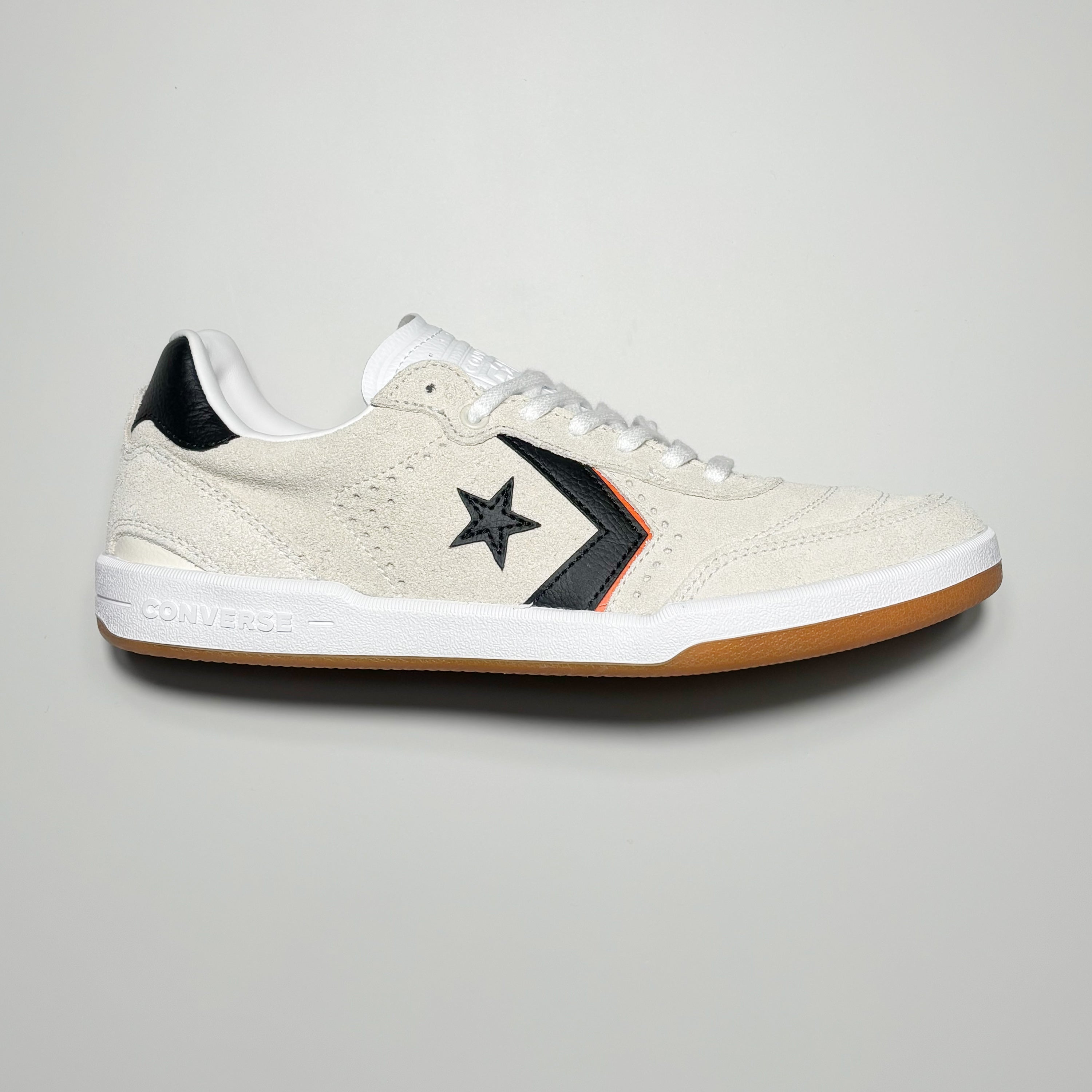 Side image of right shoe. White suede with black chevron logo and outsole.