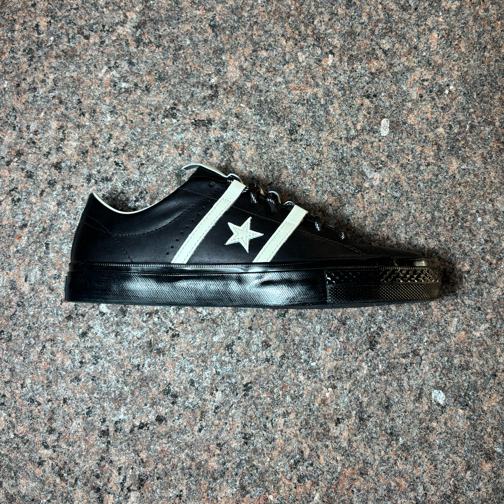 Side image of all black shoe with white stripes and star.