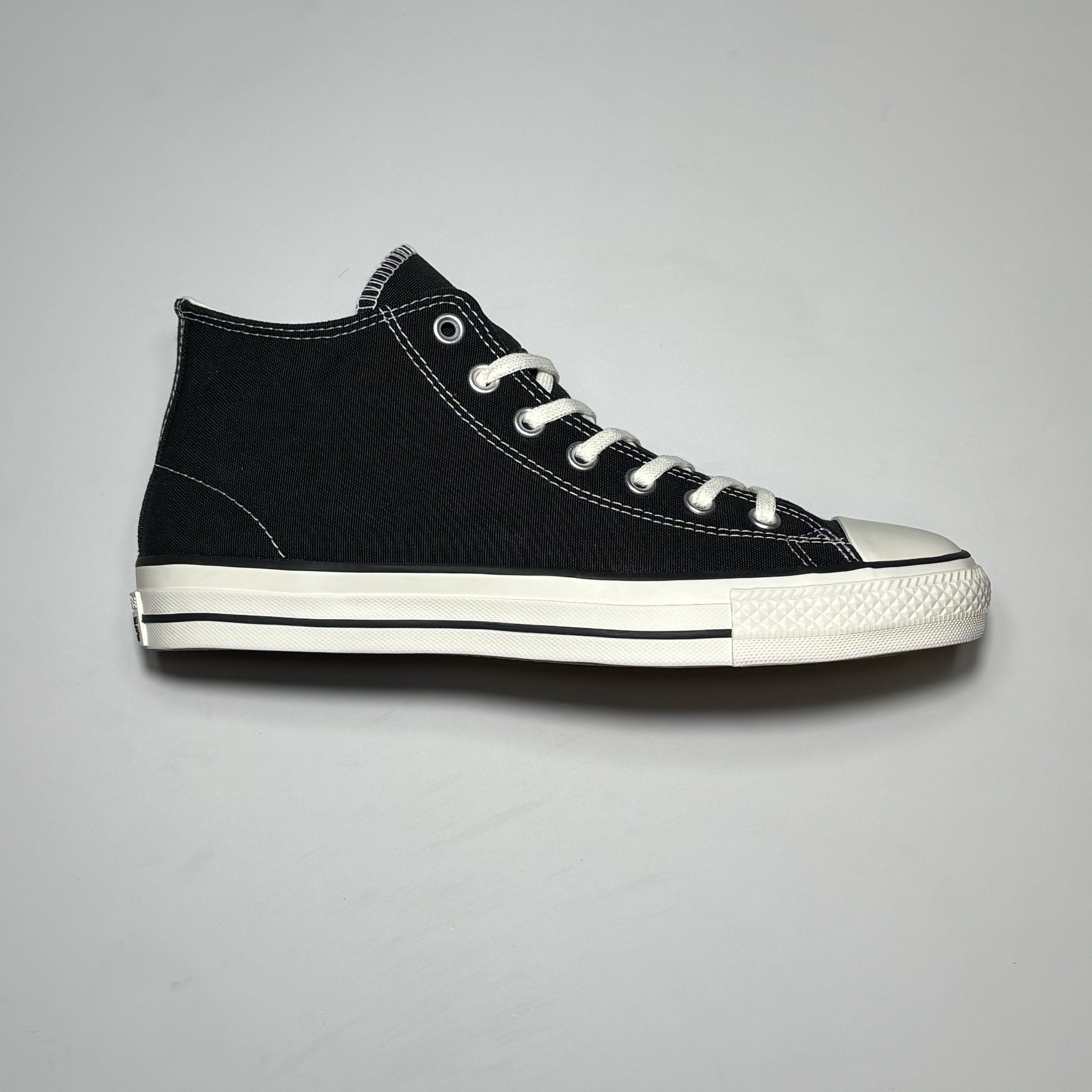 Side image of right shoe. Black canvas with with white rubber toe and outsole.
