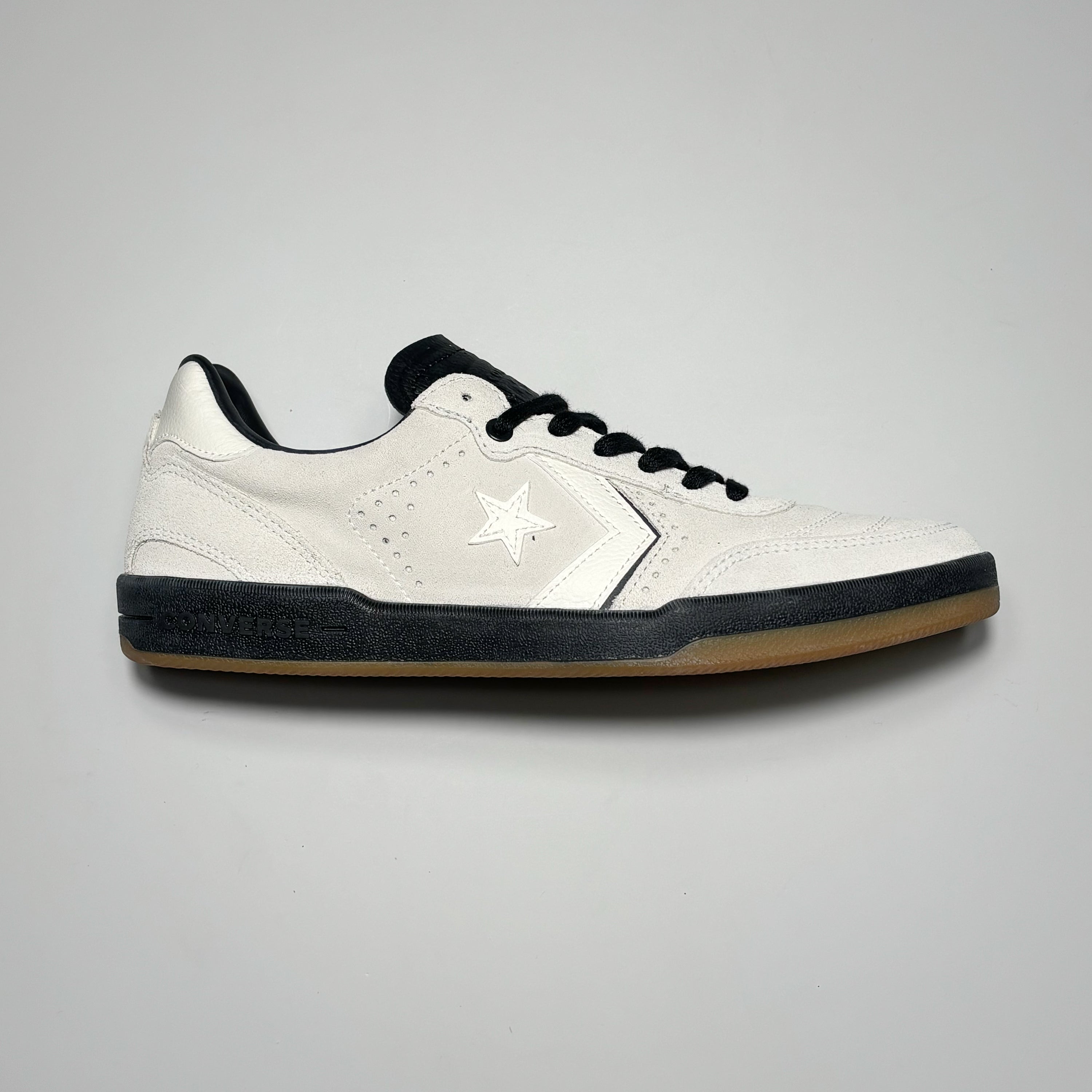 Side image of right shoe. White suede with black mid-sole.