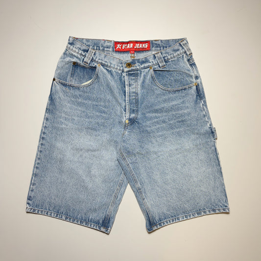Light blue denim shorts with a faded wash, featuring a red waistband label that reads 'STAR JEANS' in white text, laid flat against a light beige background.