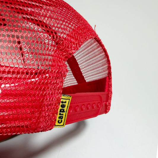 Close-up of a red mesh trucker hat showing the back mesh panels and an adjustable red strap with a yellow and black 'carpet' brand tag.