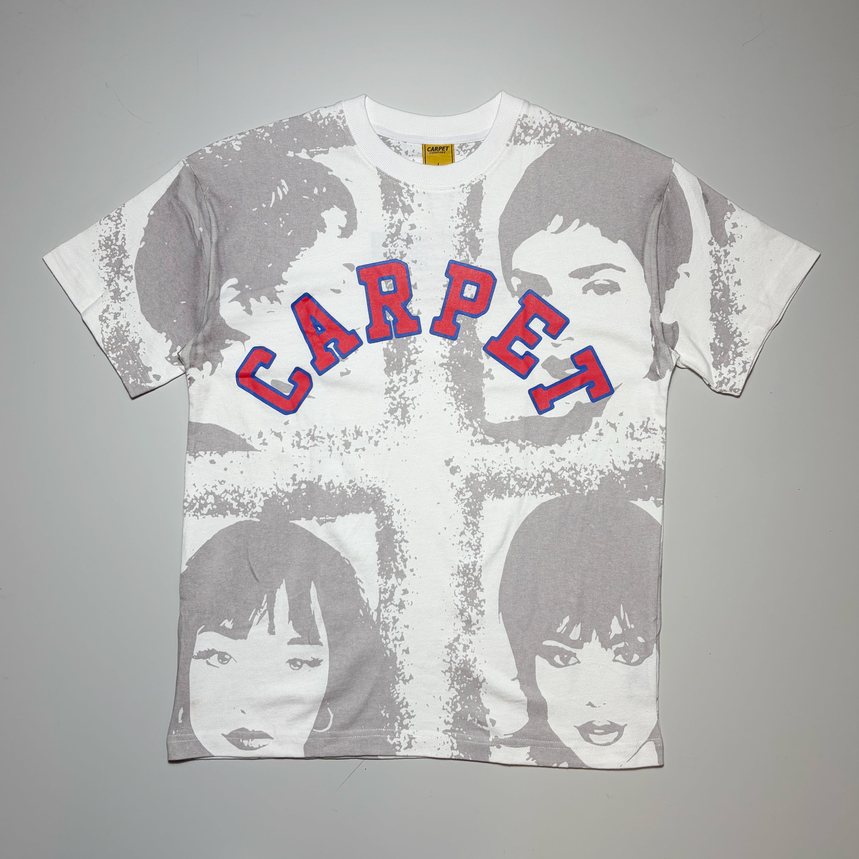 A white short-sleeve graphic t-shirt featuring a distressed gray cross design overlaid with stylized portraits of the Four Tops, with 'CARPET' printed across the chest in red letters outlined in blue.
