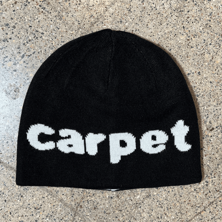 Image of black side of beanie with white carpet font woven on one side