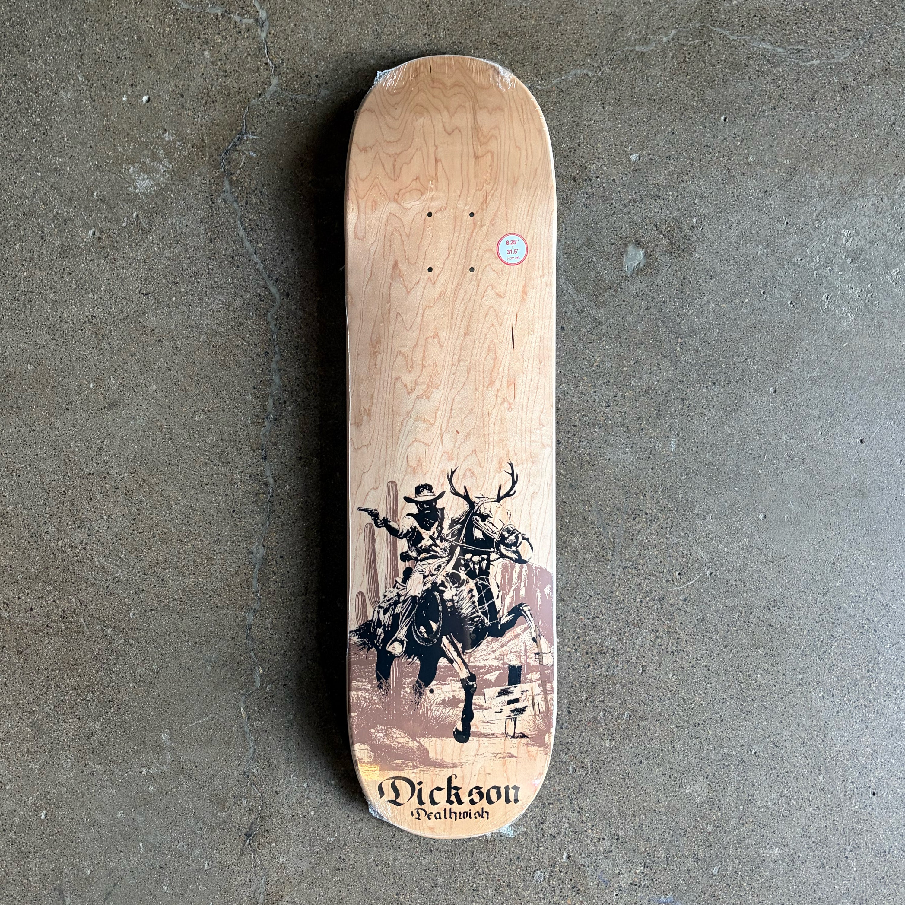Full image of skateboard deck, wood grain with black cowboy and horse artwork.