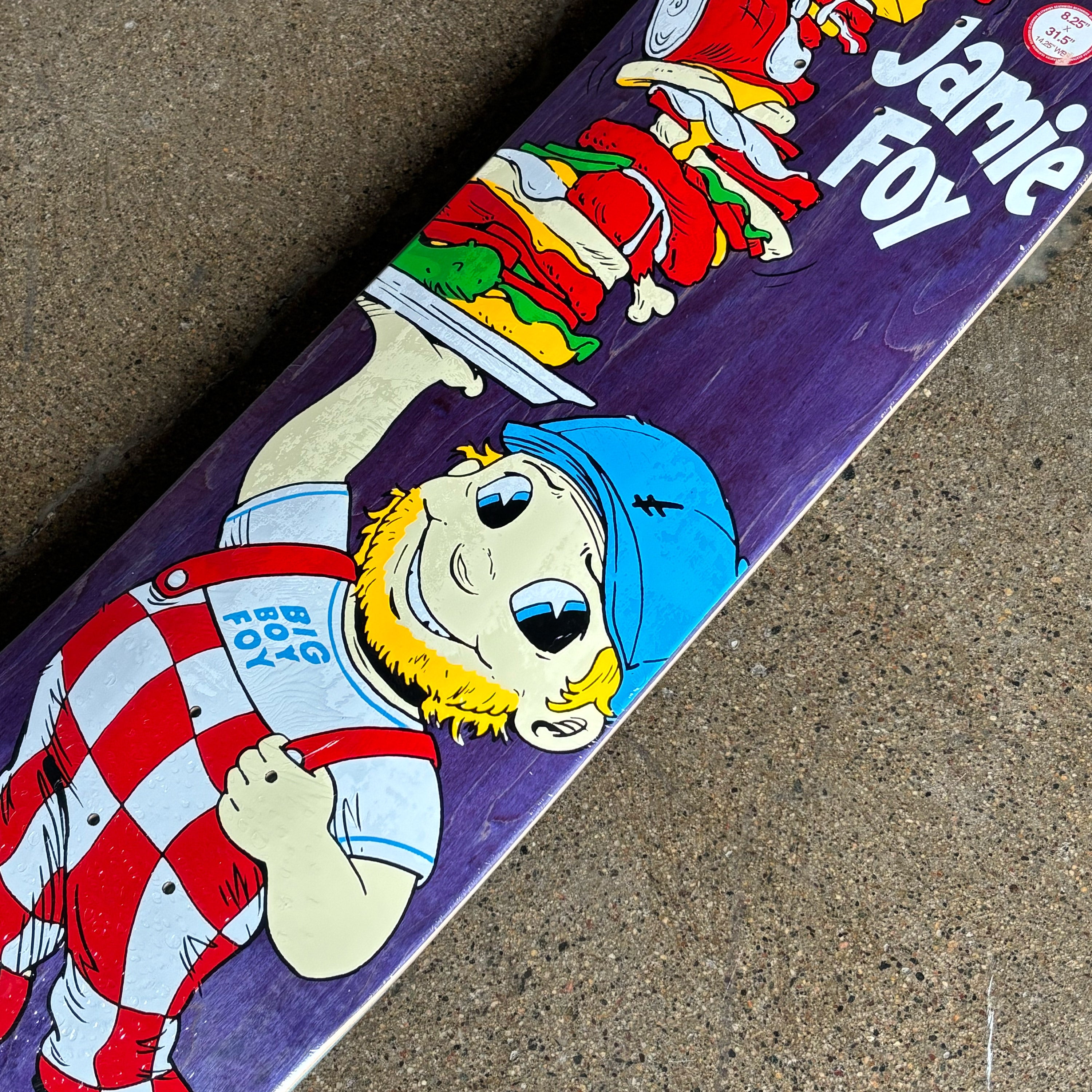 Skateboard with colorful graphics and text on a concrete surface