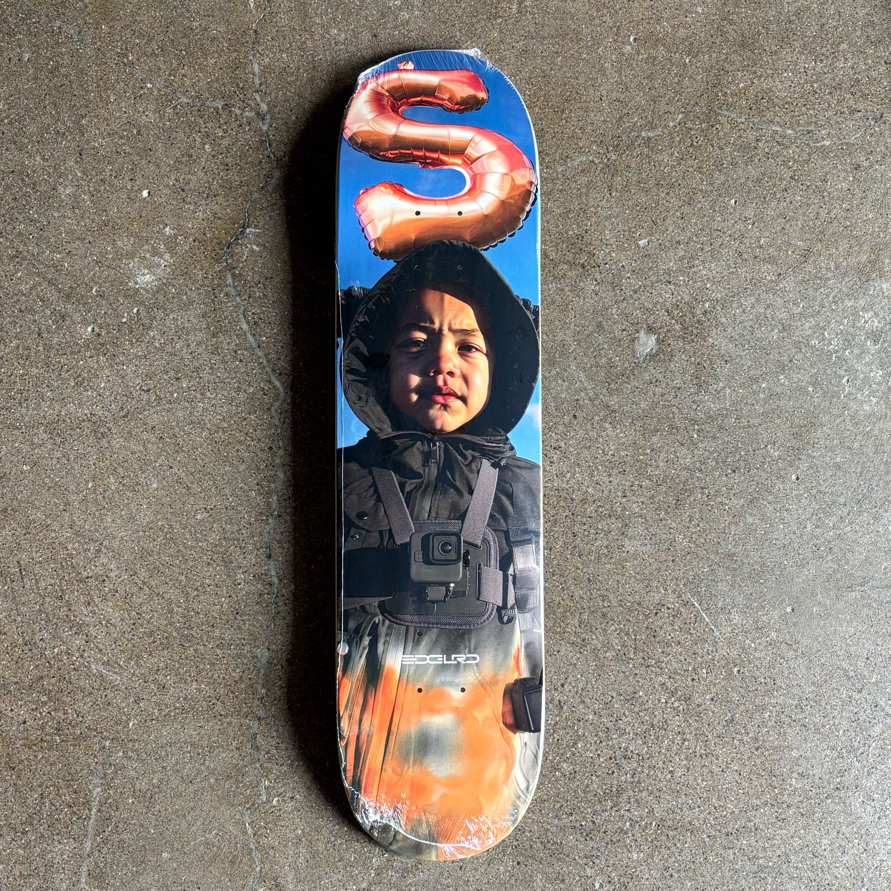 Full image of deck with a printed design of a child wearing a hooded jacket on.
