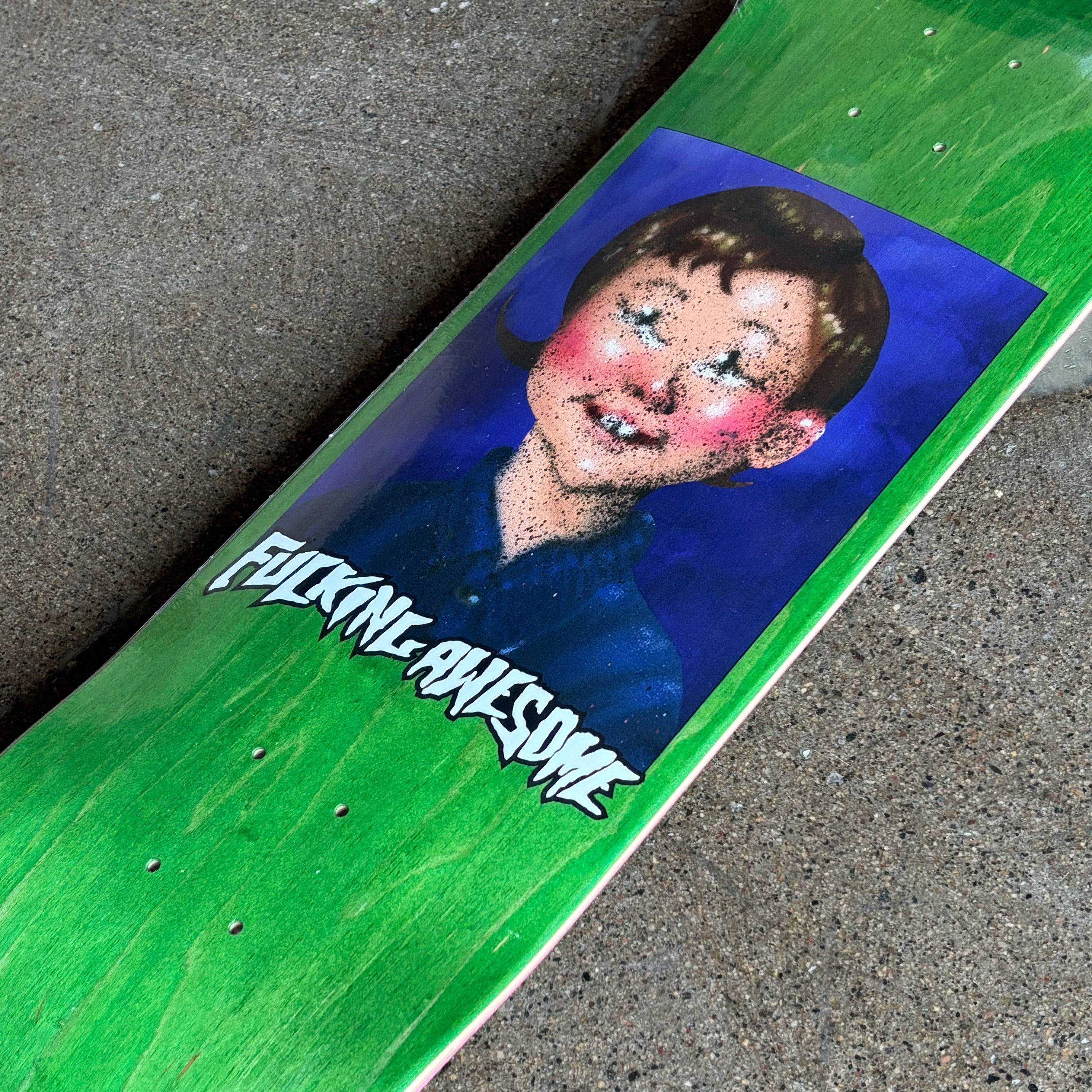 Skateboard with a graphic of a person with a blue shirt and 'Fucking Awesome' text on a green background.