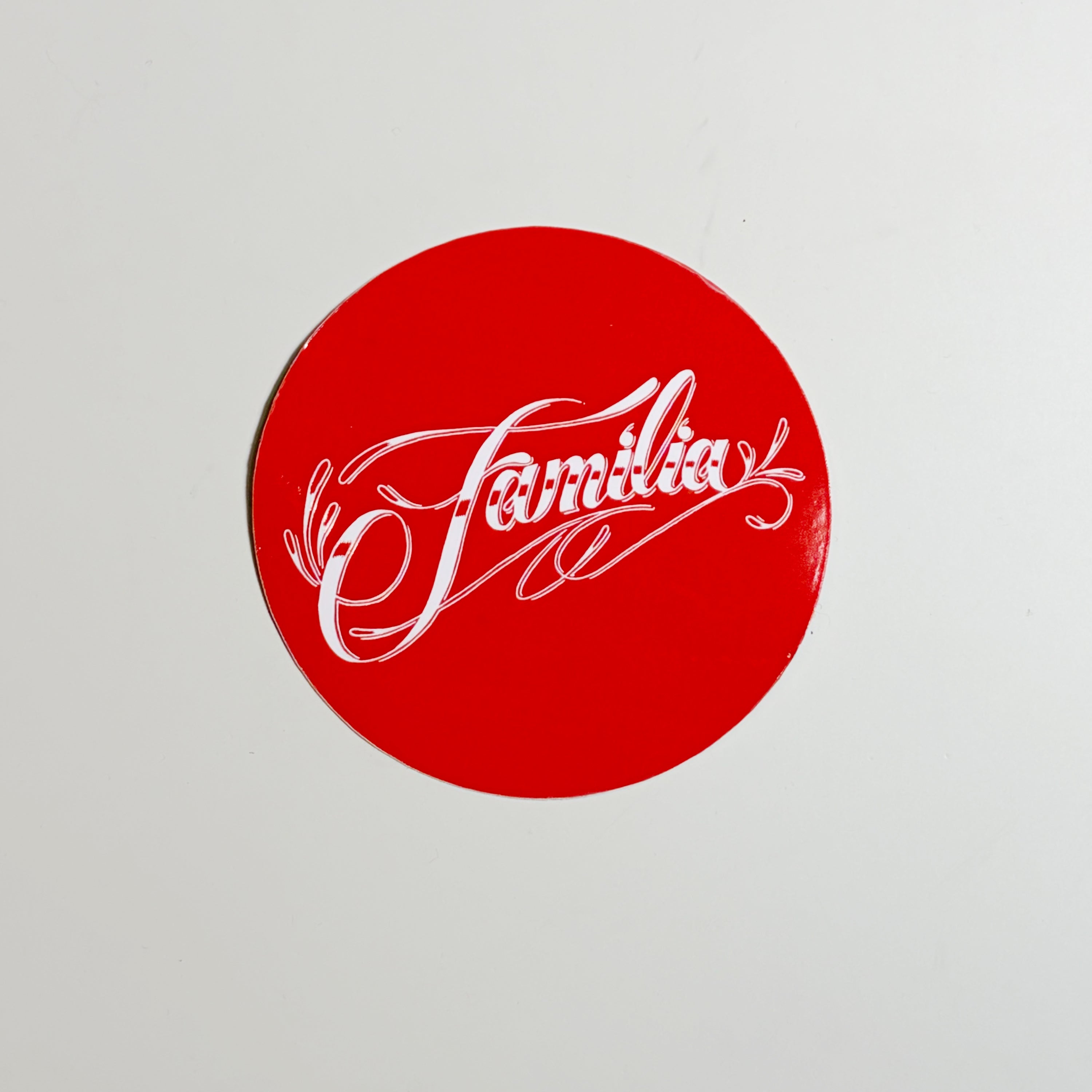 Red circular sticker with 'Familia' text on a light gray background