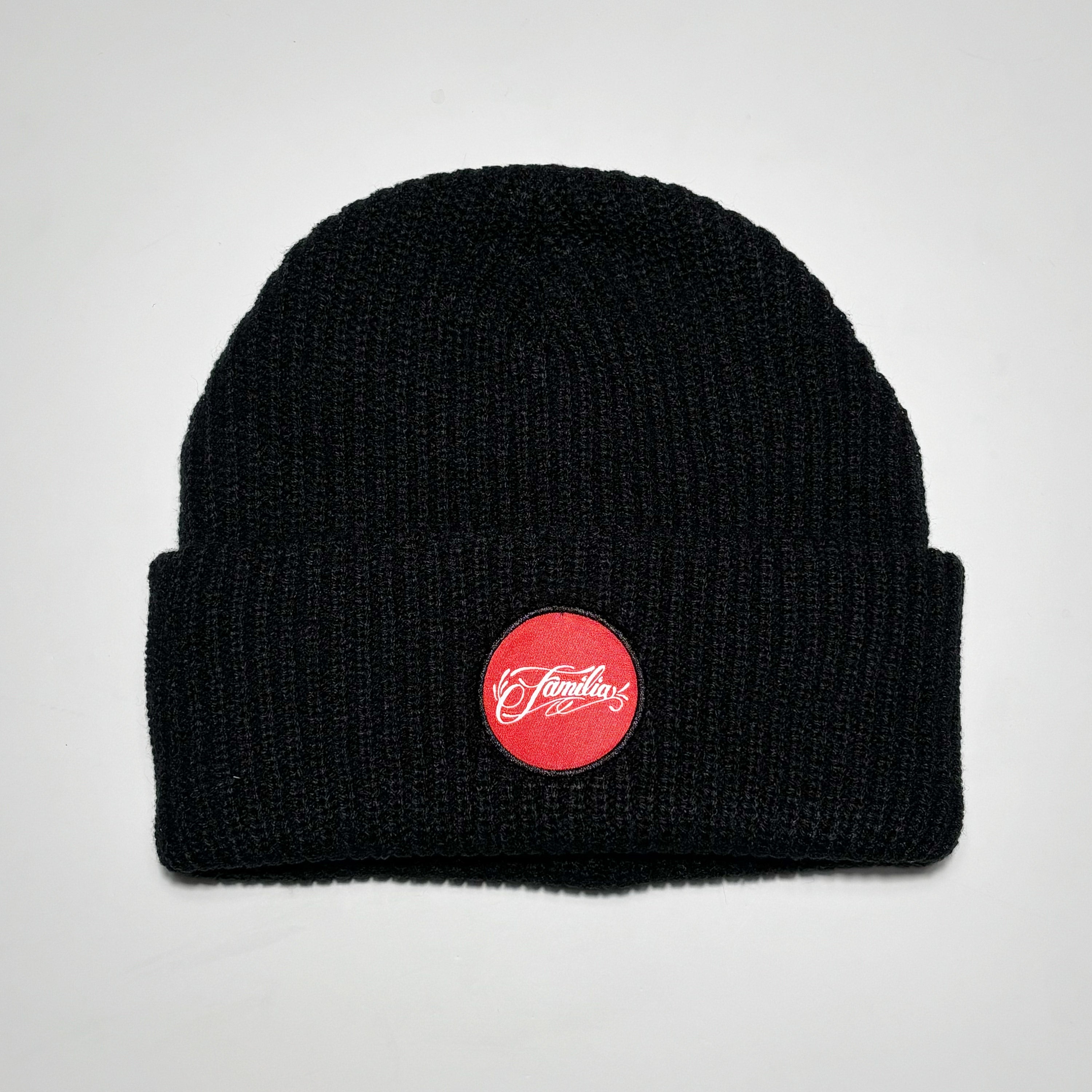 Black colored beanie with red and white familia script patch.