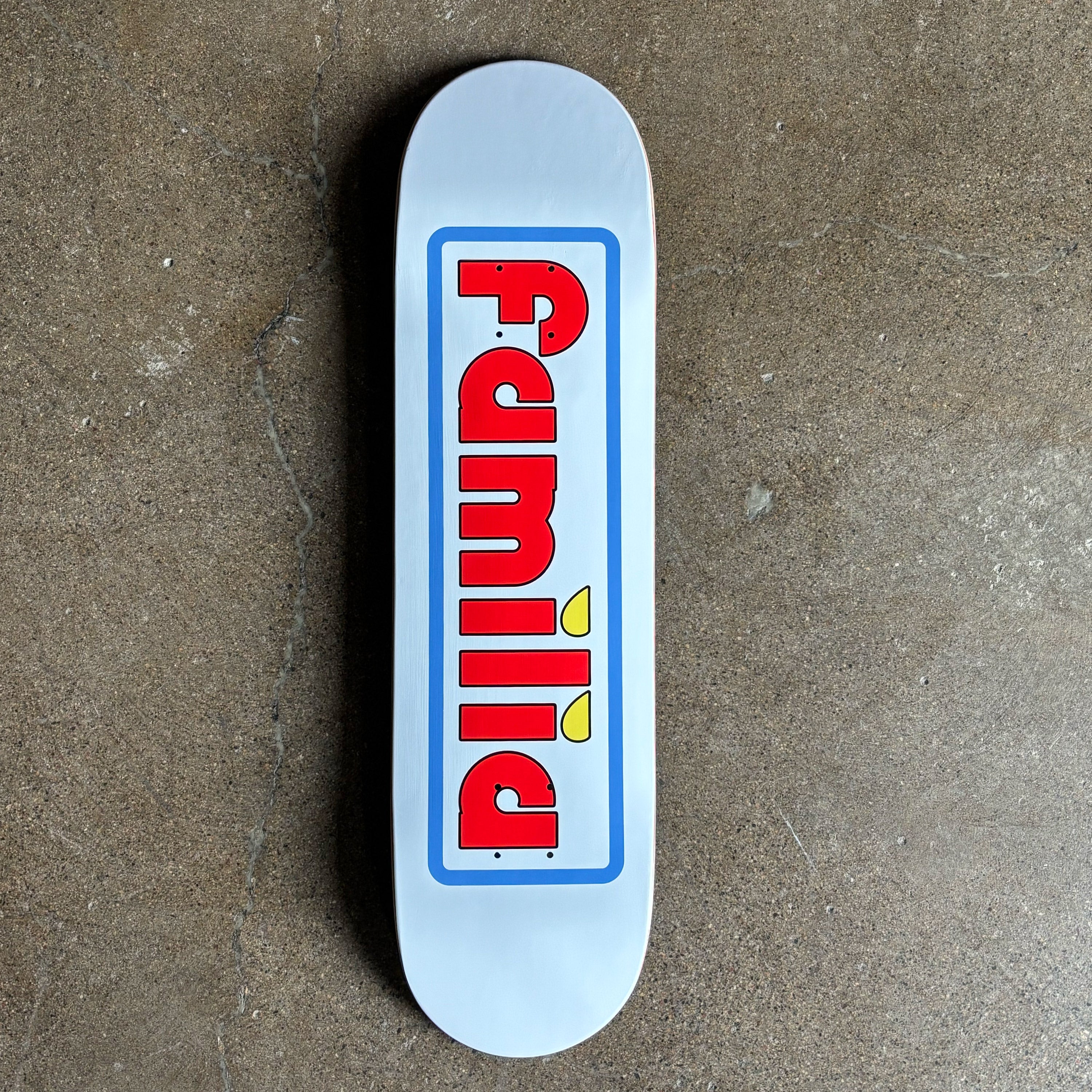 Full image of white deck with red familia font and blue outine.