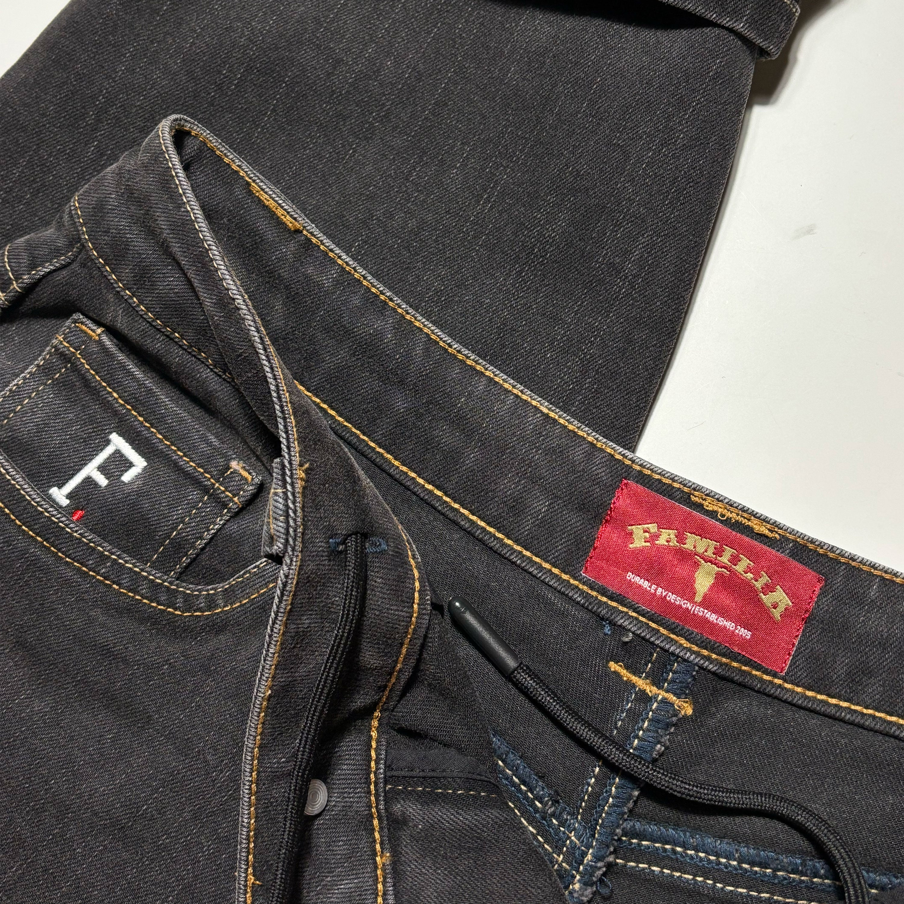 Close details of woven label inside back waistband. Embroidered coin pocket and internal drawstring.