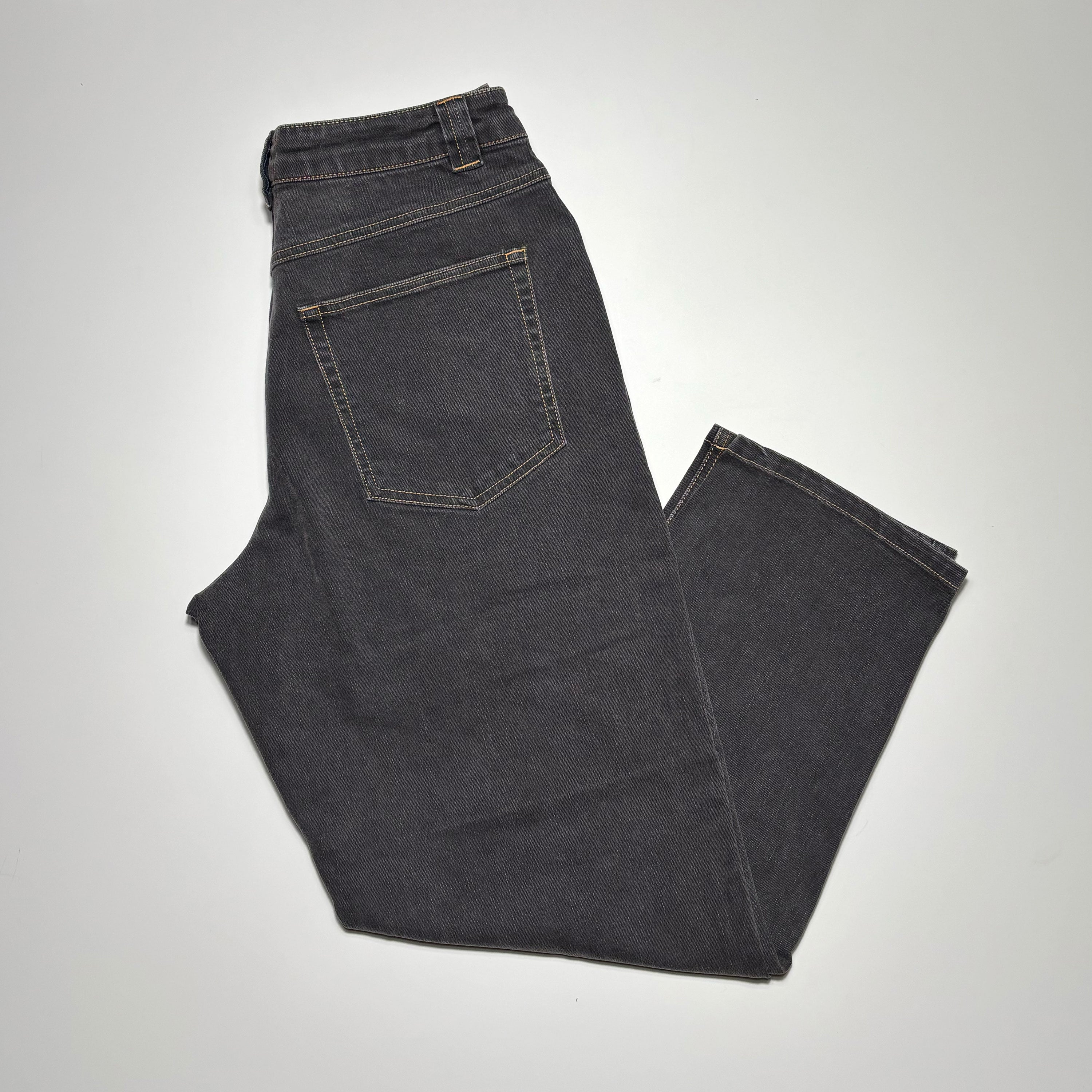 Image of folded black rinse denim with gold contrast stitch.
