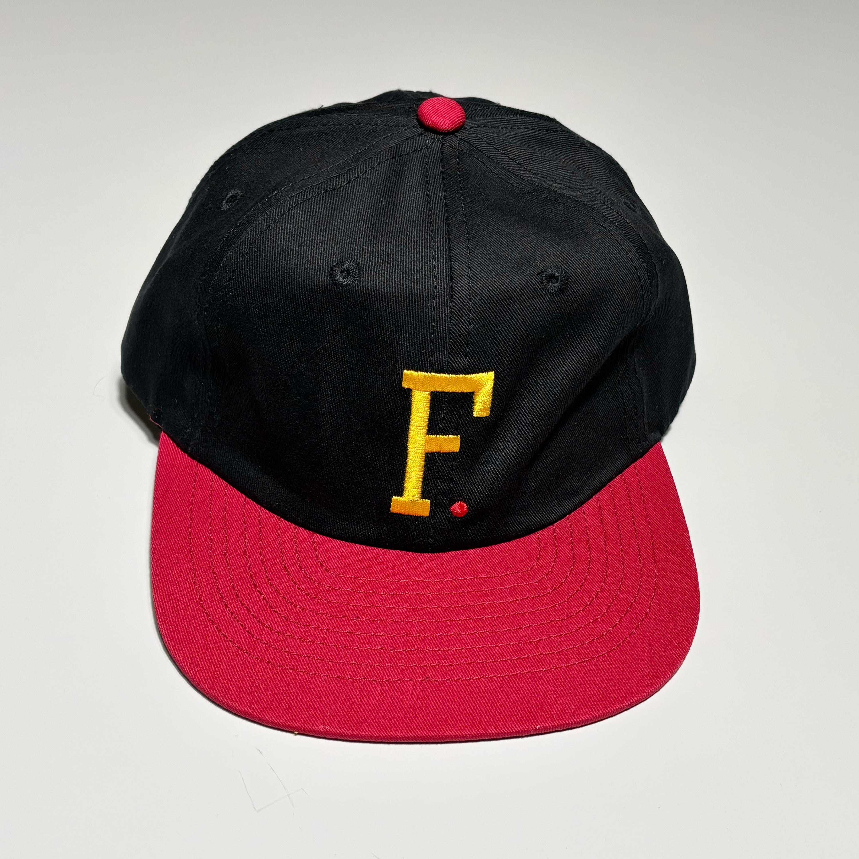 Front image of black hat embroidered art on crown with maroon brim.