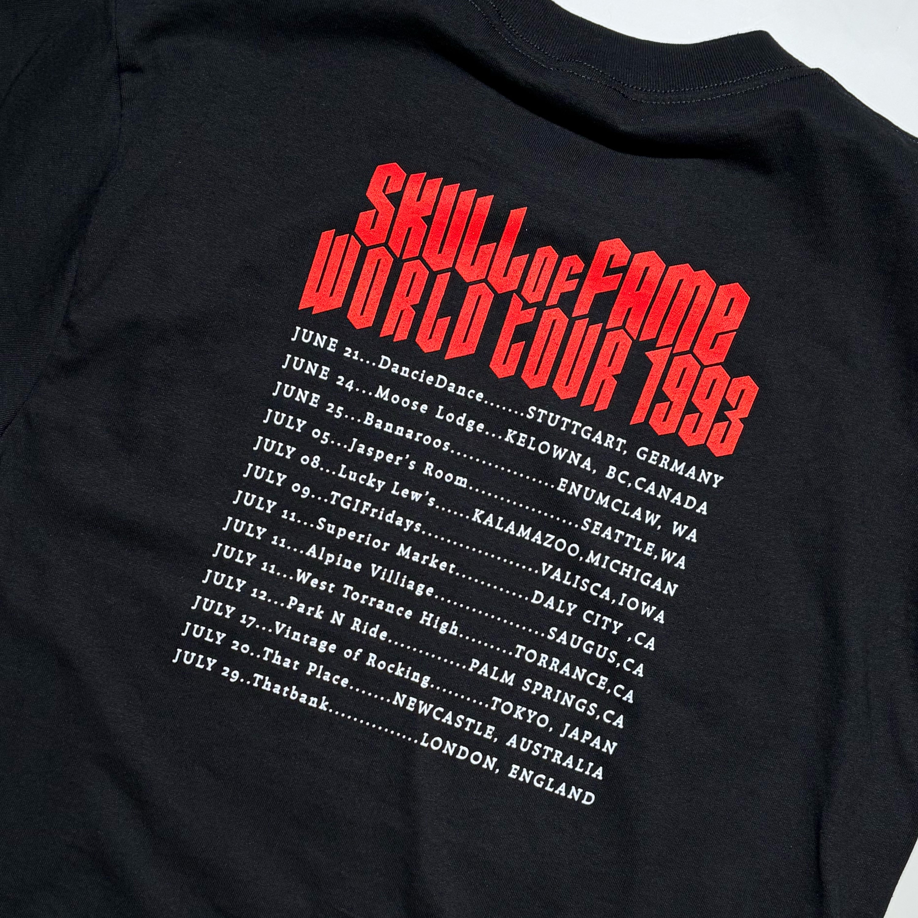 Close-up of the back of a black T-shirt with a large red and white graphic print reading 'Skull of Fame World Tour 1993' and a list of tour cities and dates in white text.