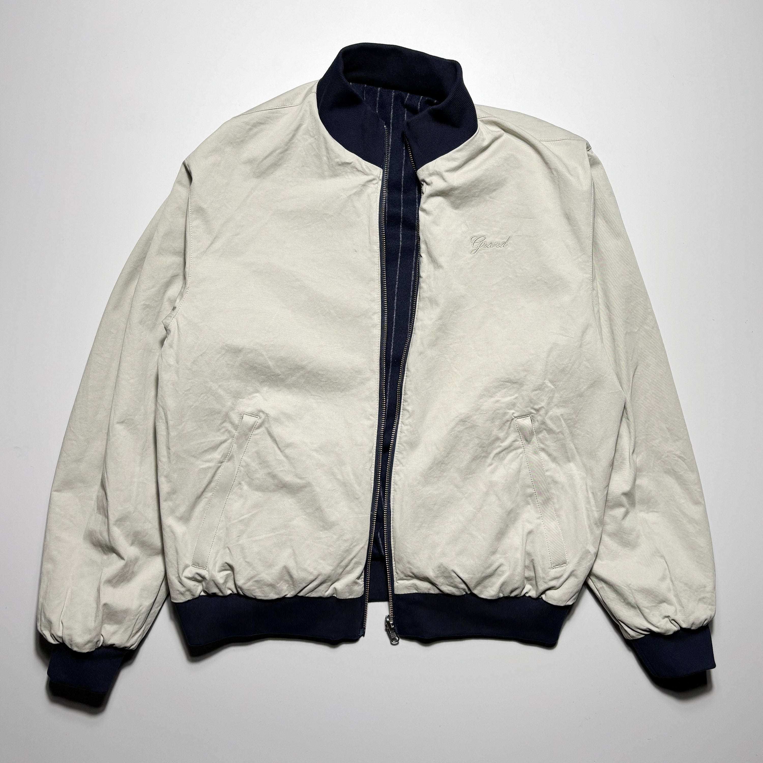 Reverse front of jacket. Cream cotton with embroidered script on chest