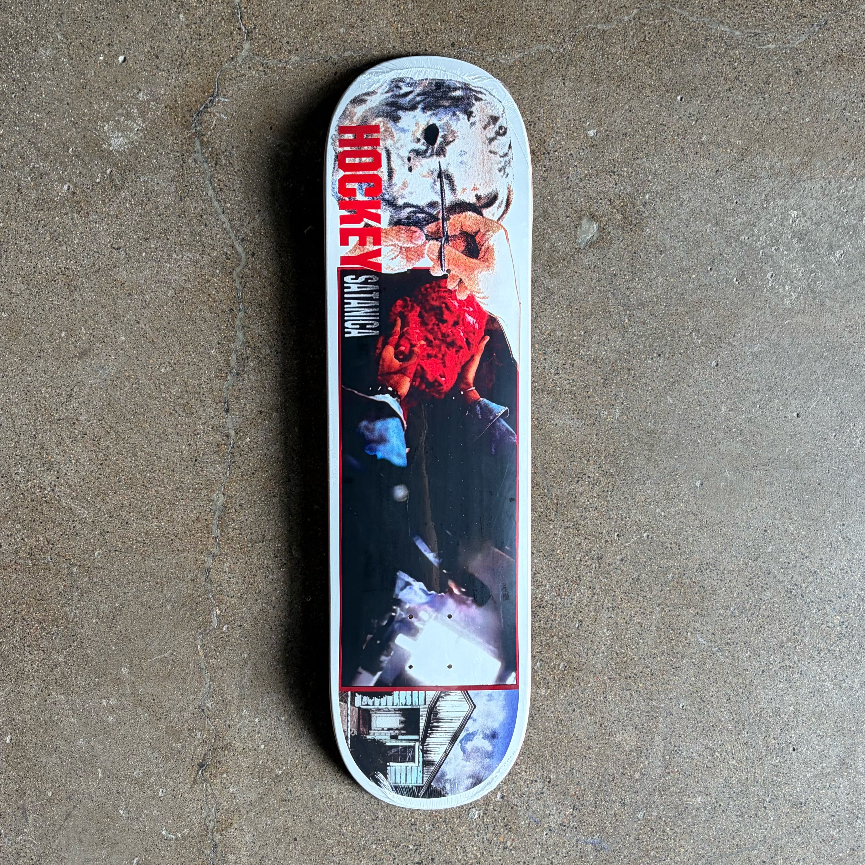 A skateboard deck with a graphic print featuring a skull, red roses, and the text 'HOCKEY SKATING' in red, photographed from above on a textured concrete floor.
