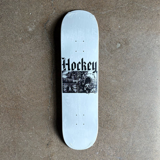 A white skateboard deck with a black graphic print featuring the word 'Hockey' in a gothic font and a black-and-white illustration, photographed from above on a textured concrete floor.