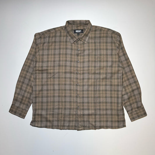 Full image of Hockey Skateboards long-sleeve button-up plaid shirt in brown and beige tones, laid flat against a light gray background.