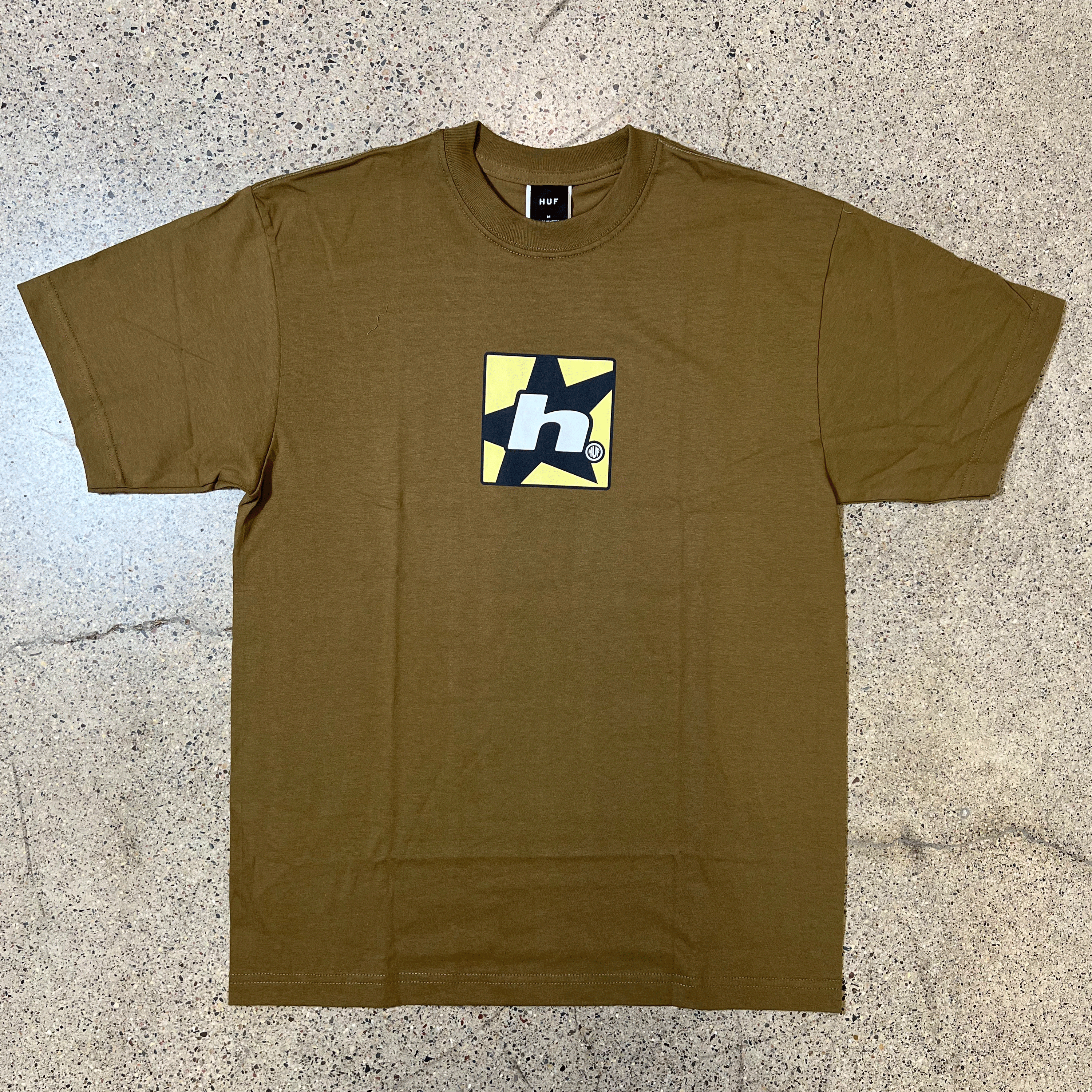 BROWN T-SHIRT, CHEST GRAPHIC OF YELLOW SQUARE WITH A BLACK STAR INSIDE AND LOWER CASE H