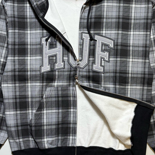 HUF double zip-up hoodie featuring a black, white, and gray plaid pattern, with 'HUF' embroidered in varsity block letters across the chest. Fleece lined.