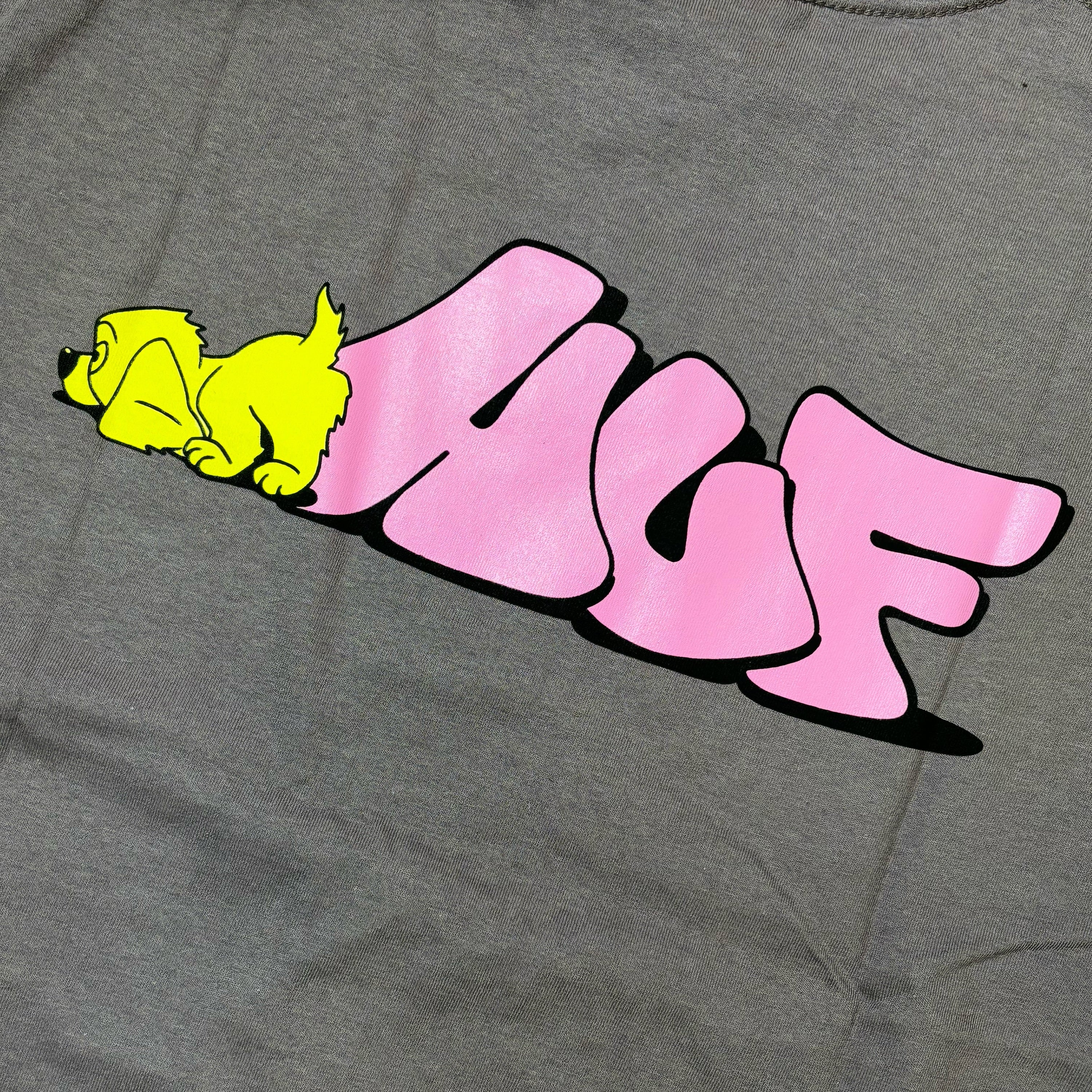 Detail image of sniffing yellow printed dog with pink printed HUF logo on back of plum color tee