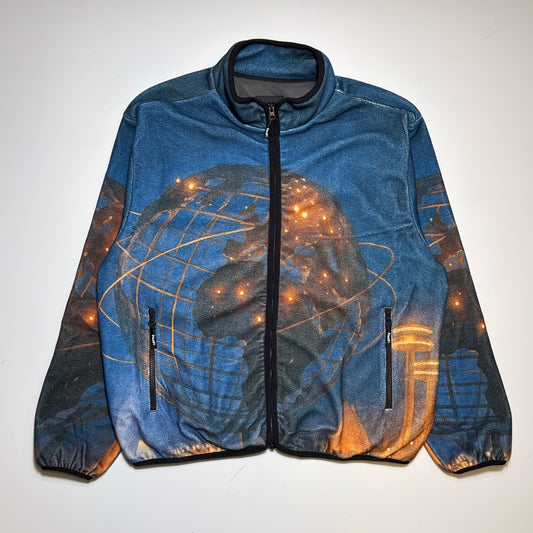 HUF Polar fleece in blue zip-up jacket with a digital printed graphic of a globe and glowing city lights, laid flat against a light background.