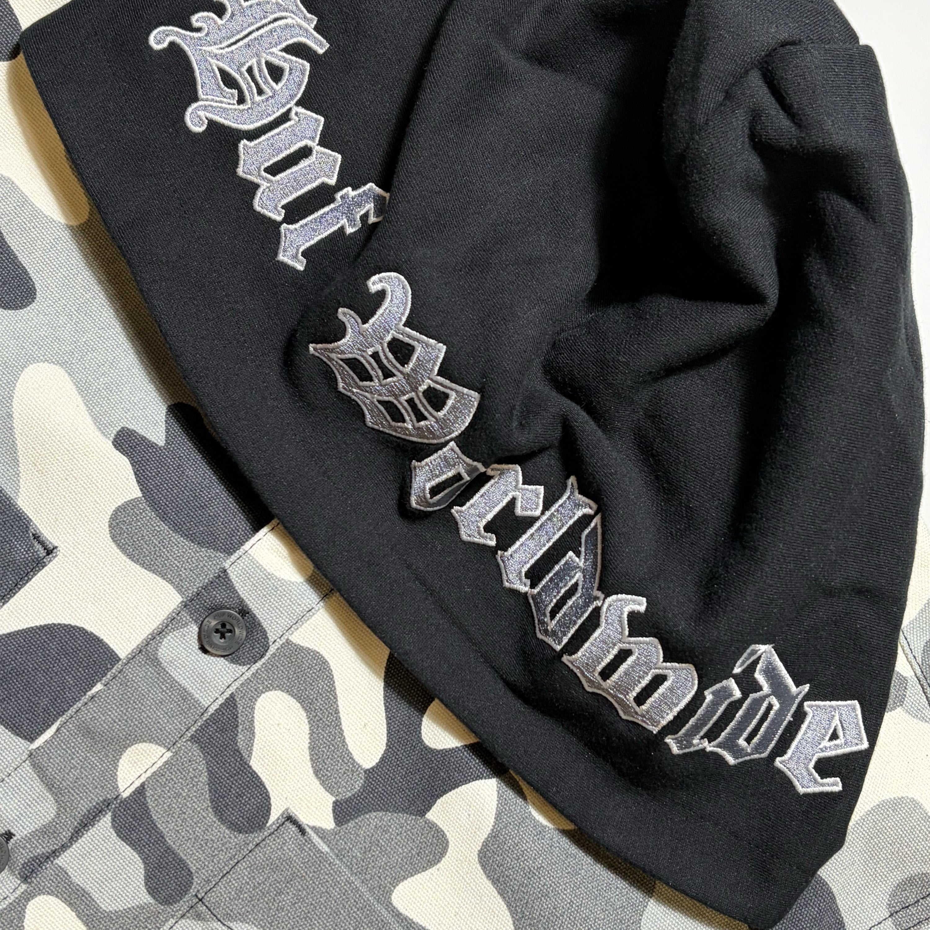 Close detail of HUF Worldwide embroidered hood on camo jacket overshirt. 