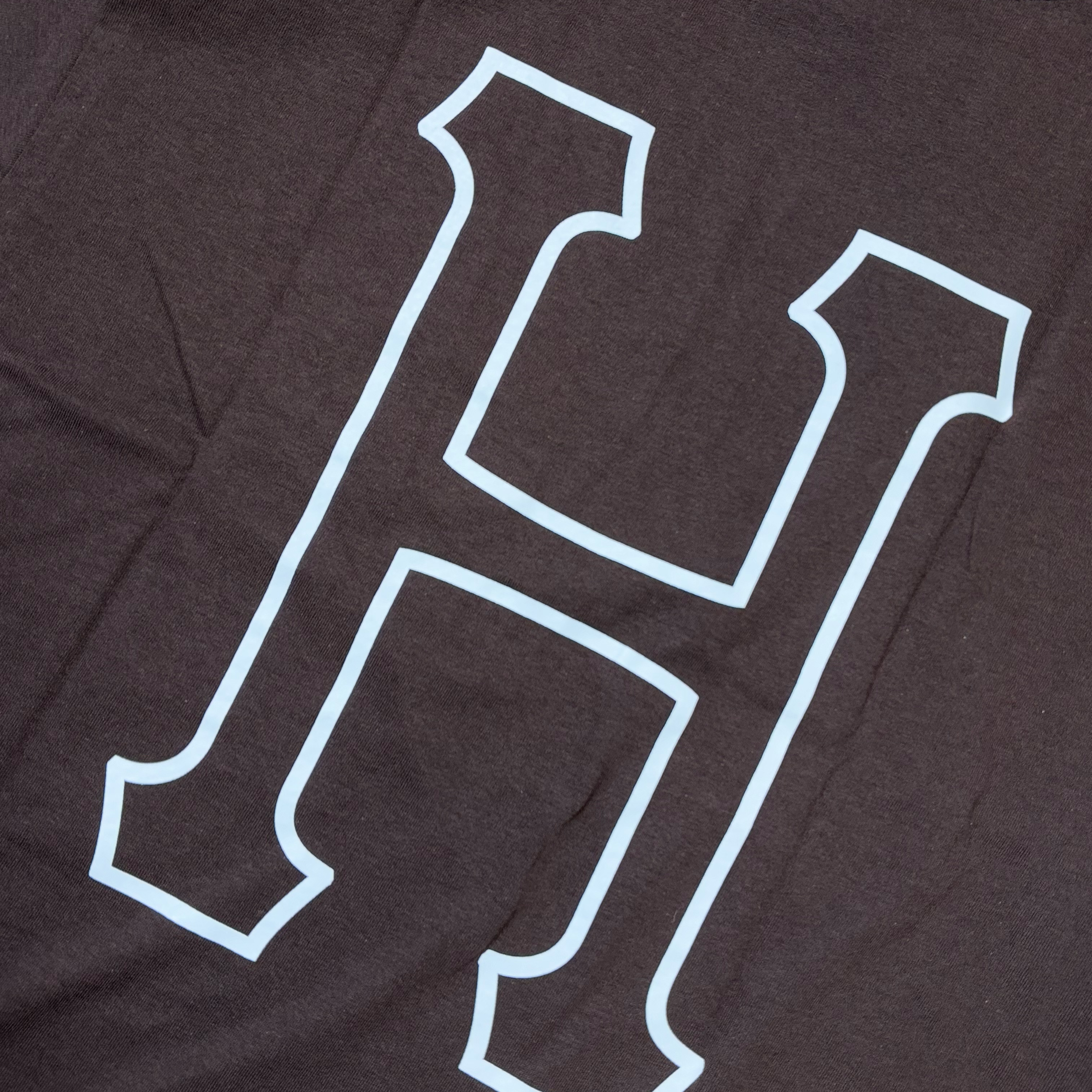 Detail of white printed H on back of espresso color  tee