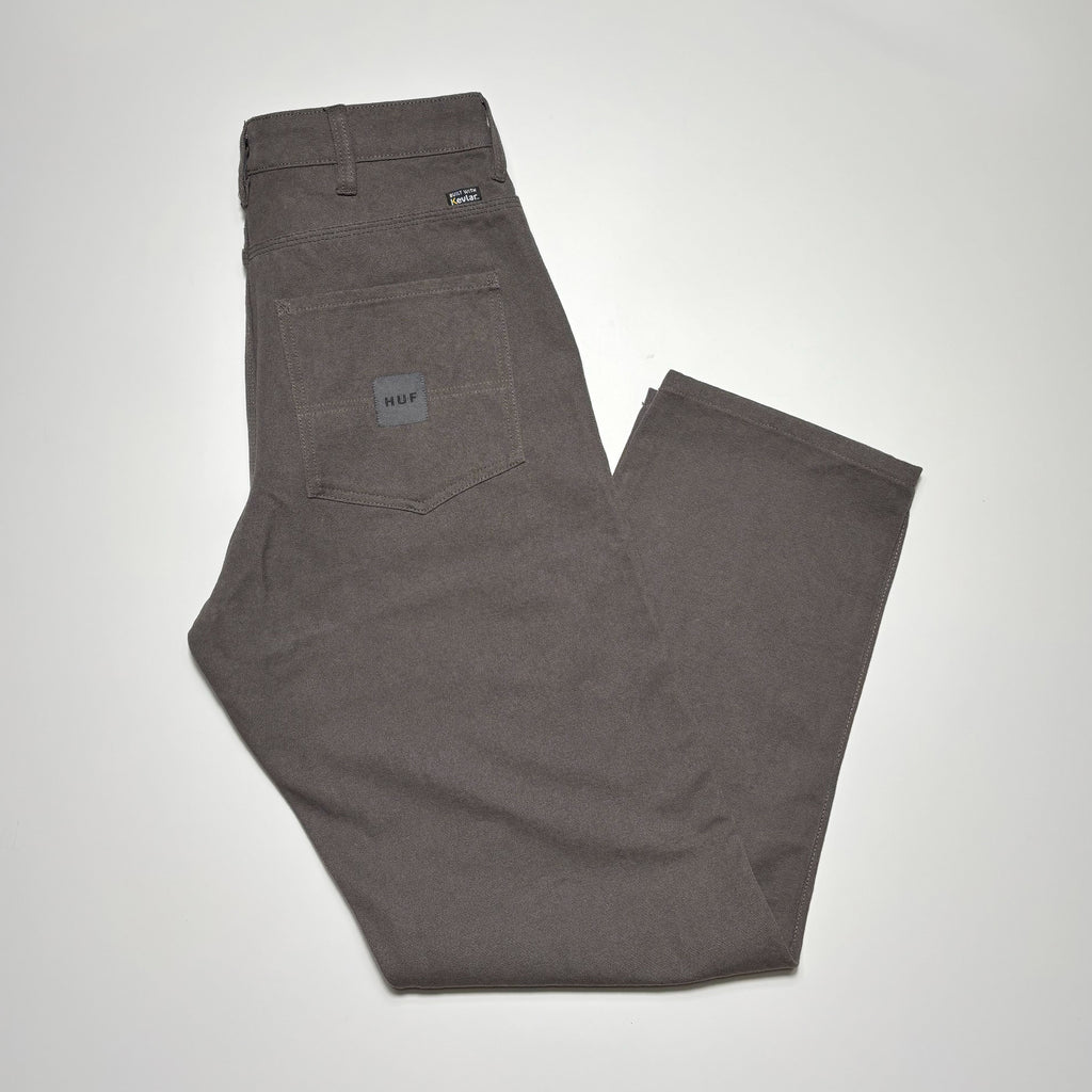 Image of folded pant in cement grey with HUF woven label on back pocket.